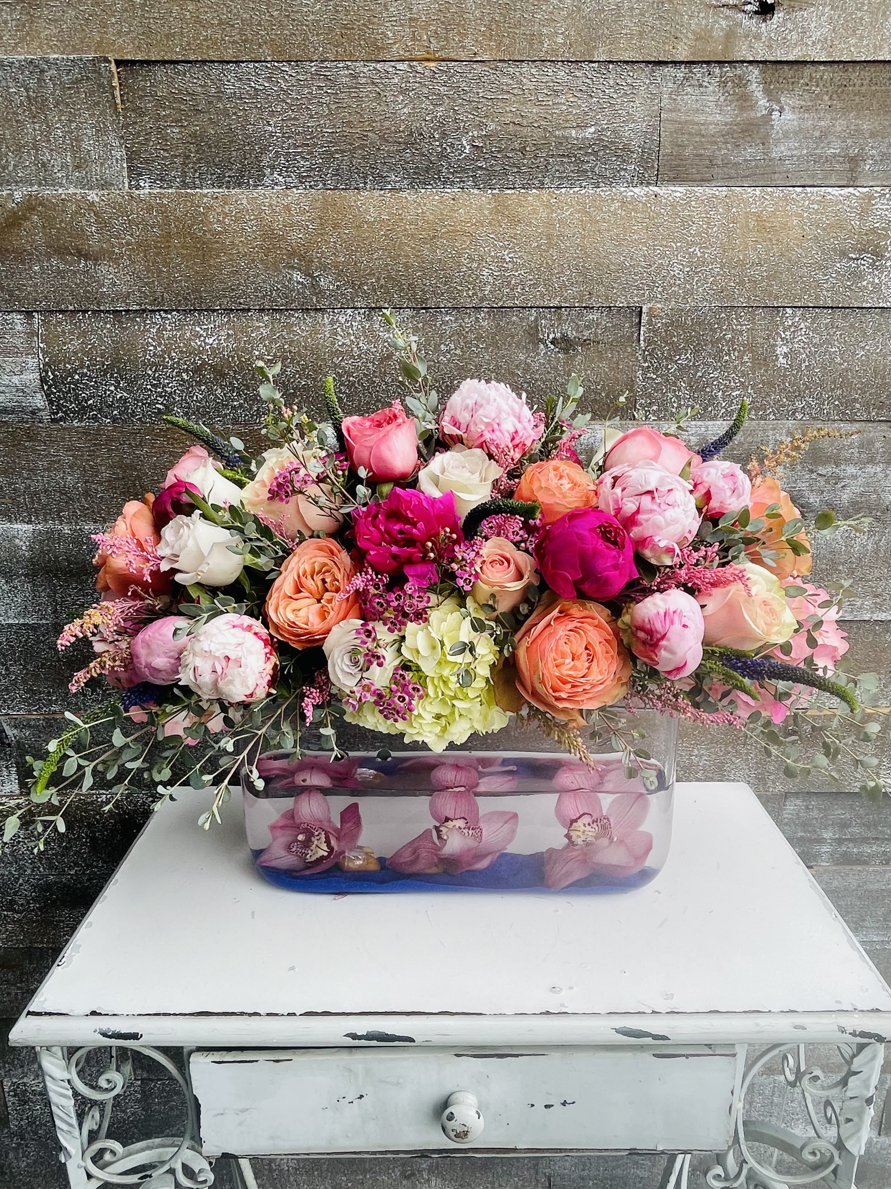 Mixed pink and peach flower arrangement in a rectangular glass vase