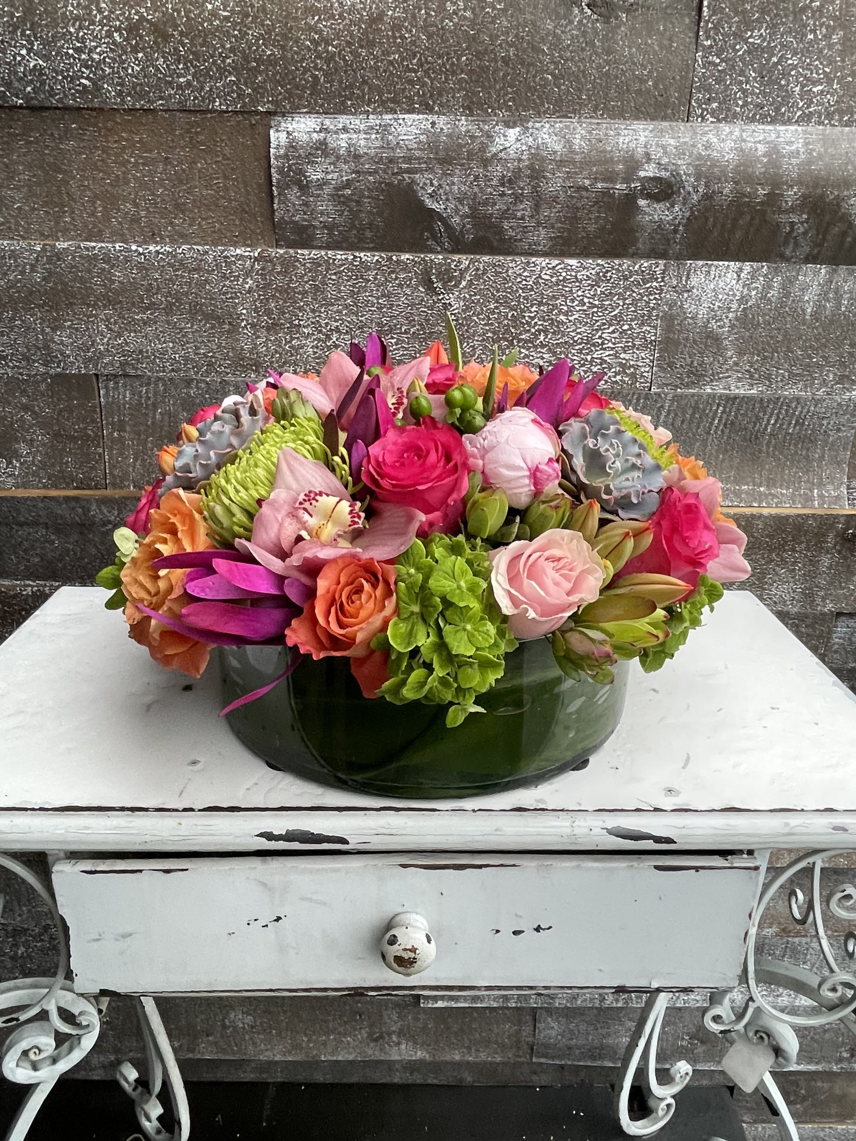 Colorful mixed flower arrangement in a low green glass bowl
