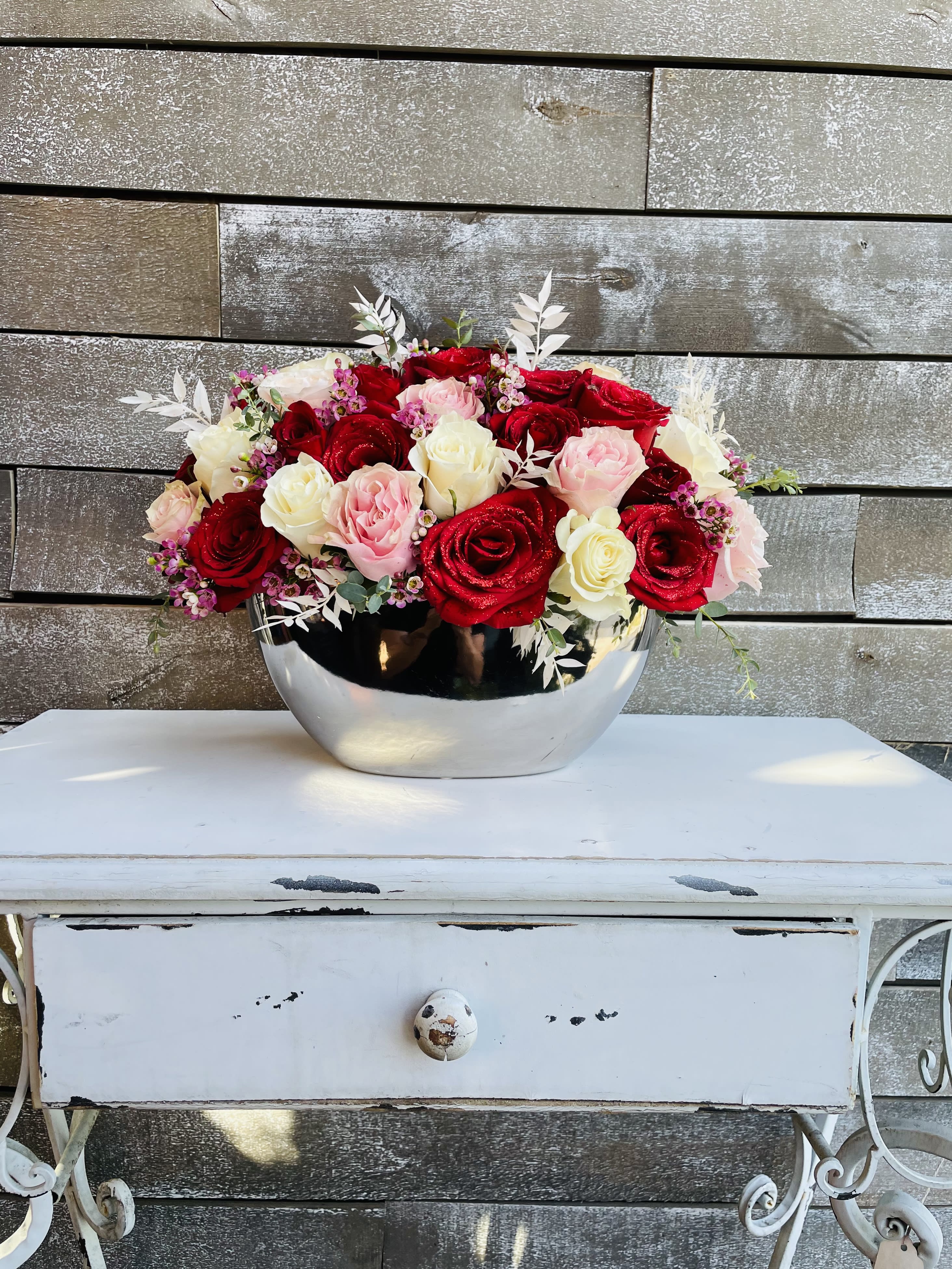 Red, pink, and white roses arranged in a silver bowl