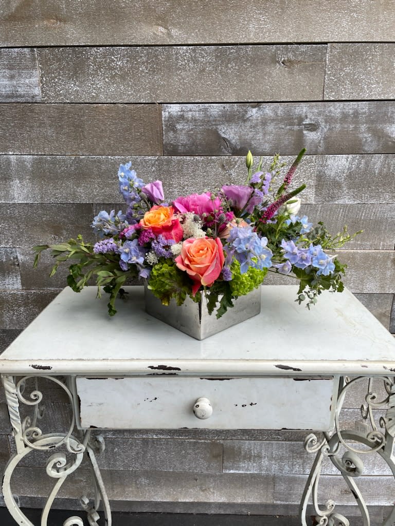 Colorful mixed flower arrangement in a square metal container