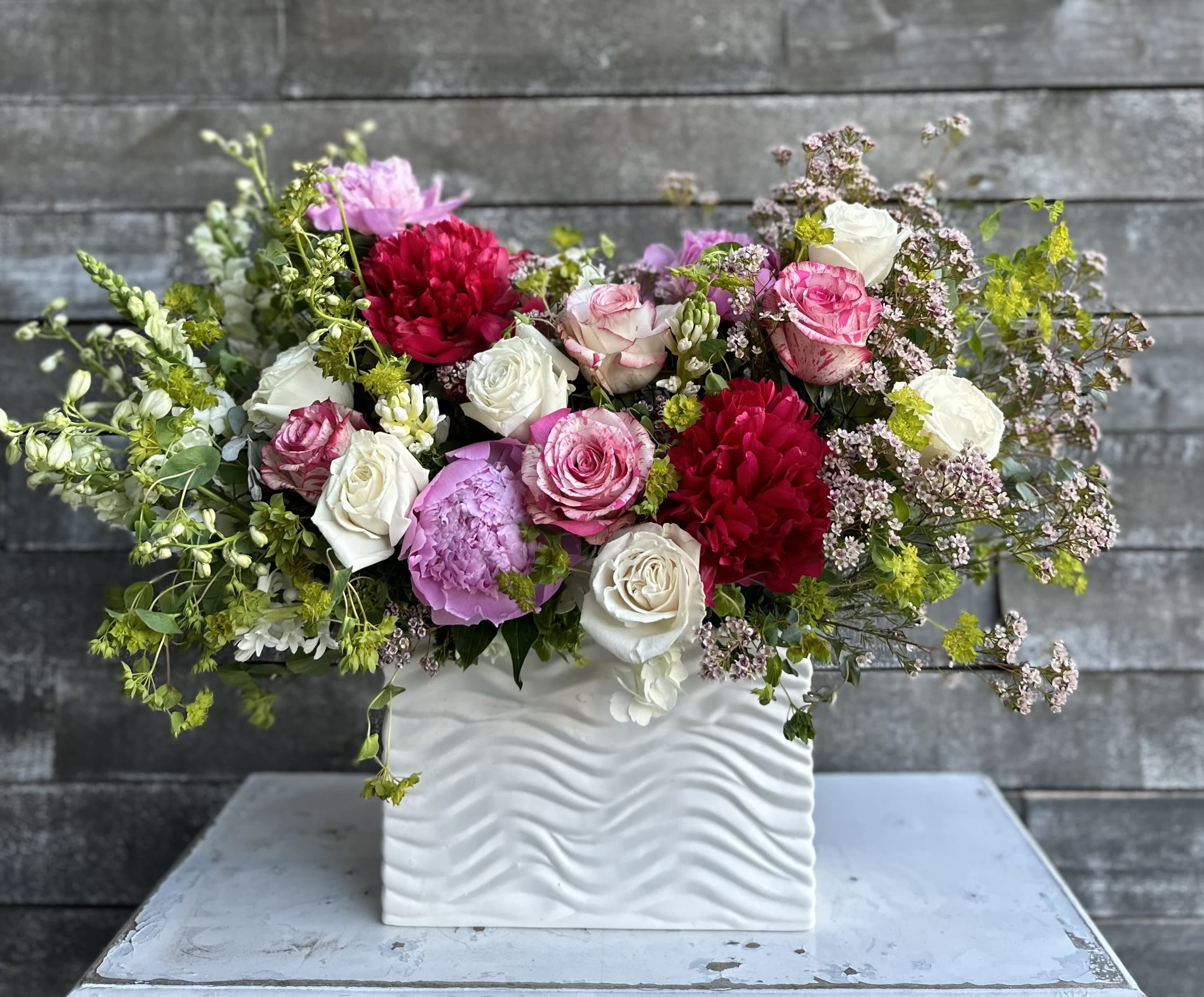 Mixed pink, white, and red flowers in a white textured vase