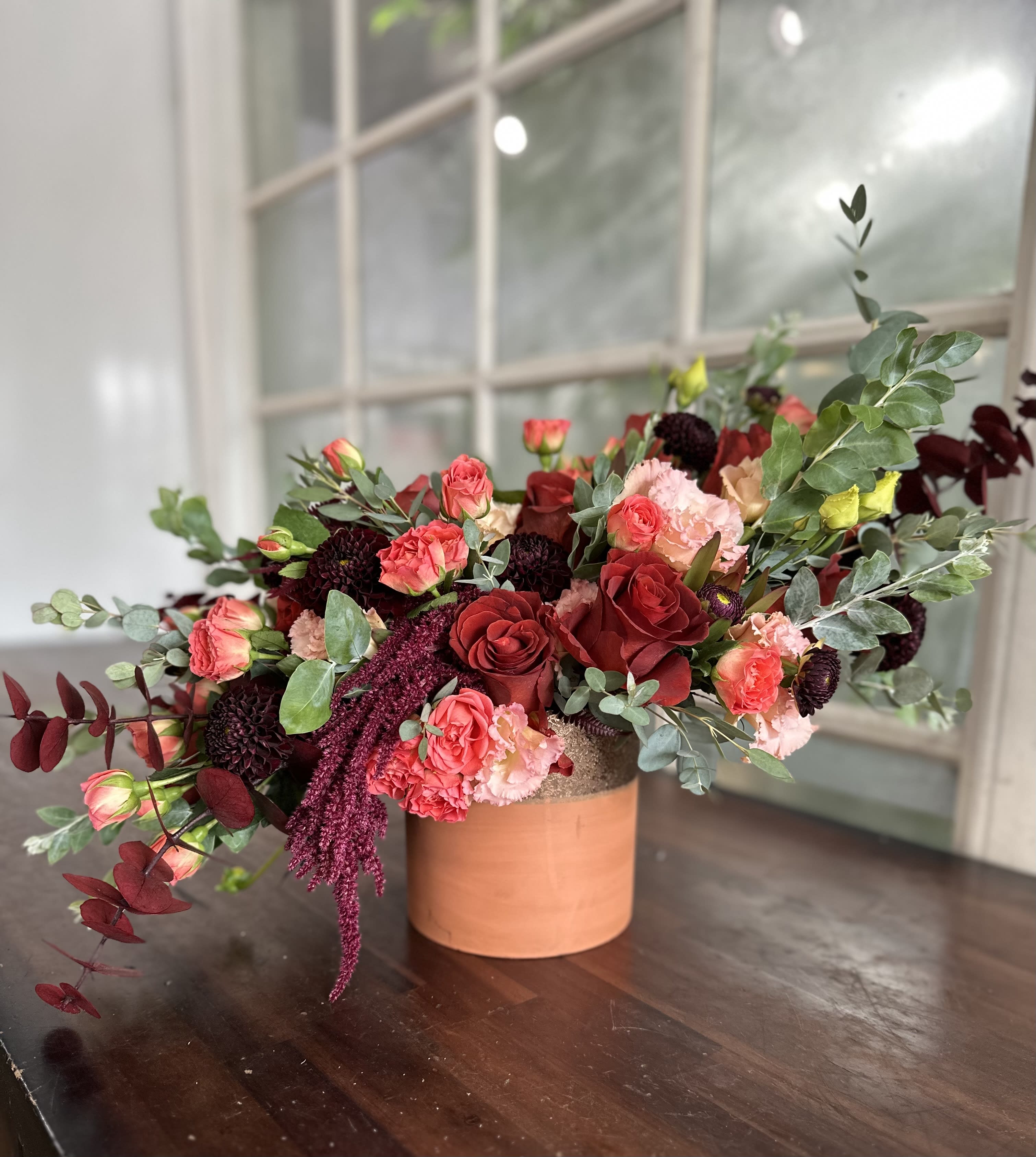 Red and pink rose arrangement in a terracotta vase