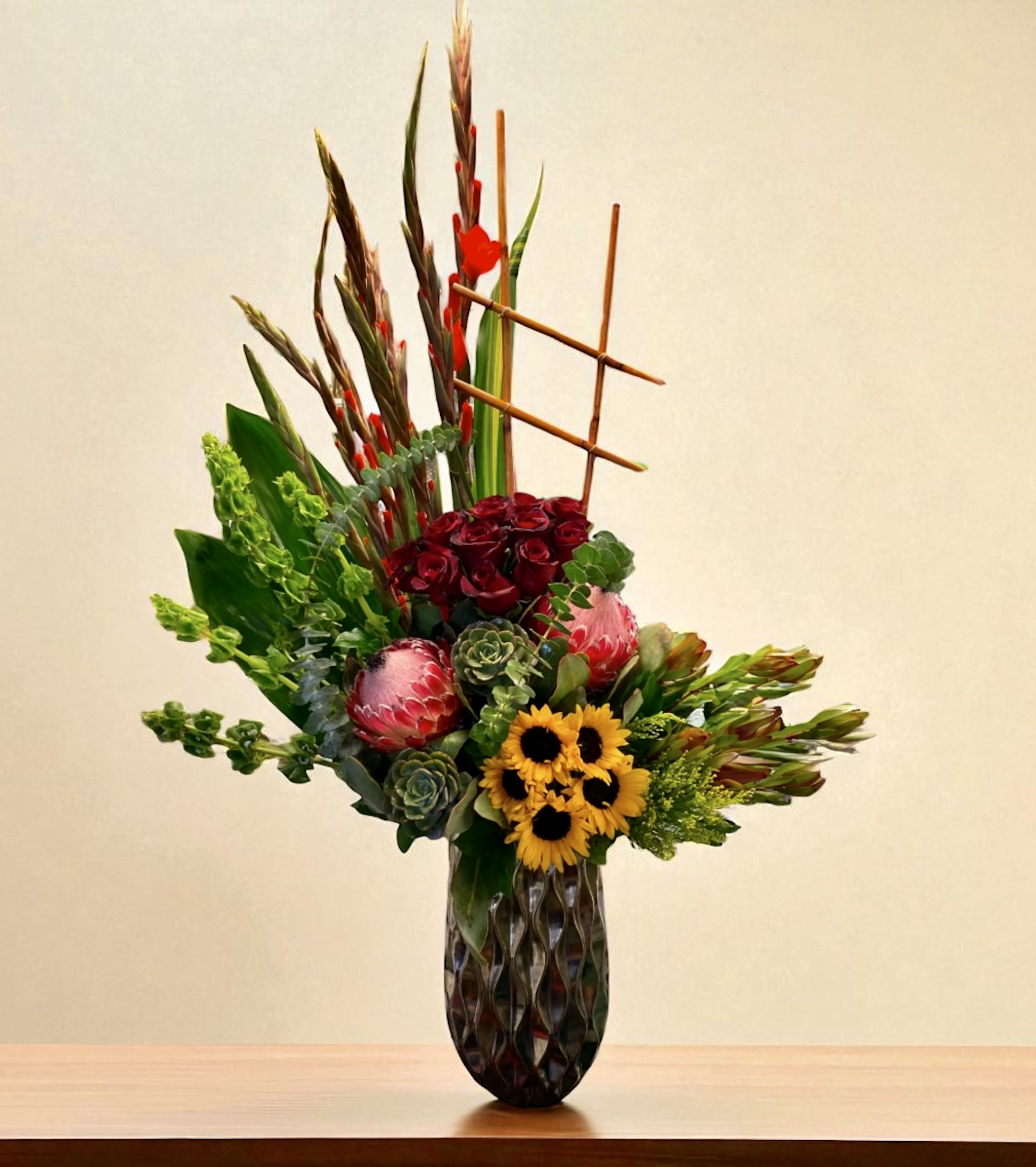 Tall mixed floral arrangement in a dark vase with red, yellow, and green blooms