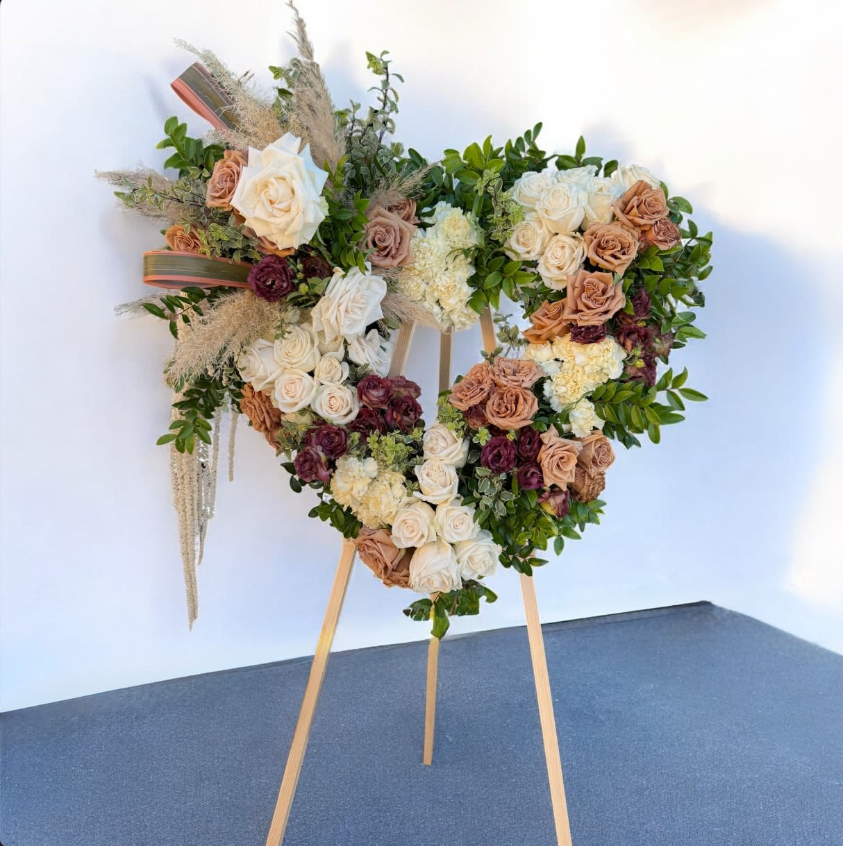 Heart-shaped floral arrangement on an easel with roses and greenery