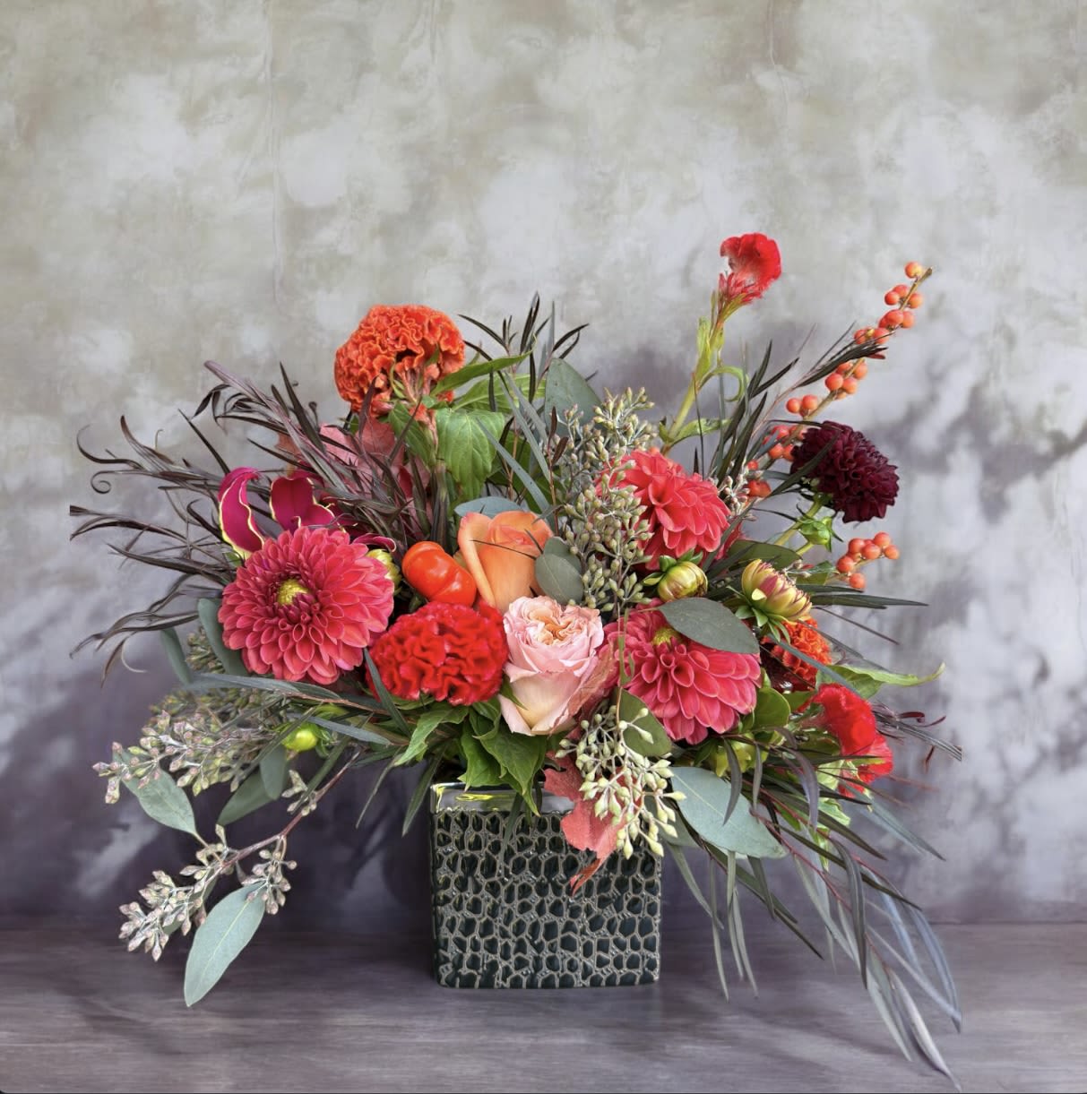 Bright mixed flower arrangement in a square textured vase