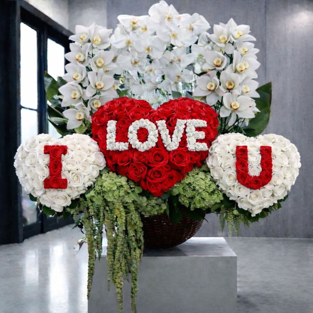 Heart-shaped rose arrangement with white orchid sprays and floral letters