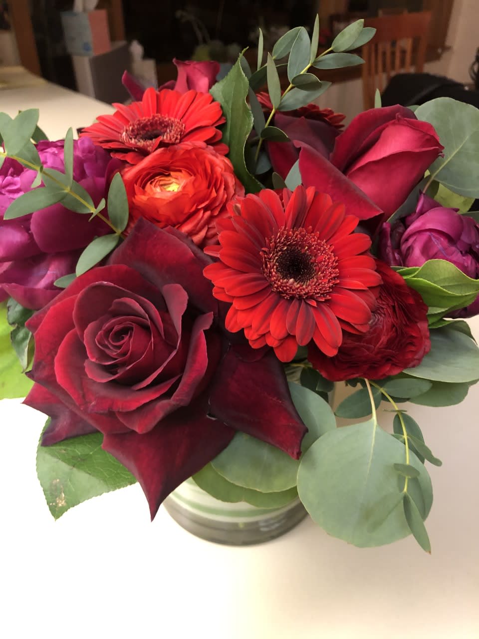 Bouquet of red roses and gerbera daisies in a glass vase