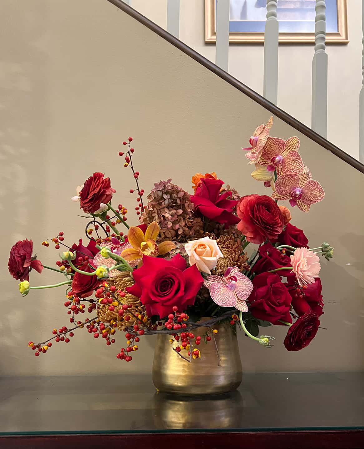 Mixed red and pink flower arrangement in a gold vase