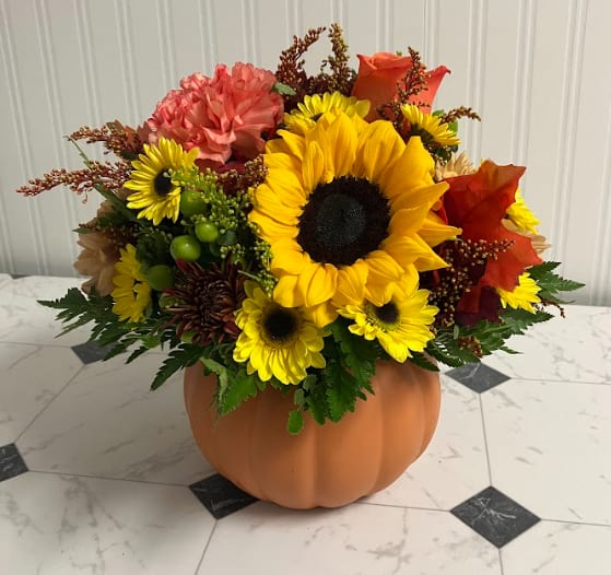 Hello, Pumpkin - Celebrate the season in full color with this cheerful arrangement designed in a classic orange pumpkin. Overflowing with bright autumn blooms in bold shades of orange, yellow, and red, it’s a festive favorite that instantly warms up any space. Whether as a centerpiece, a seasonal gift, or a splash of fall décor, this arrangement is the perfect way to say hello to autumn.
