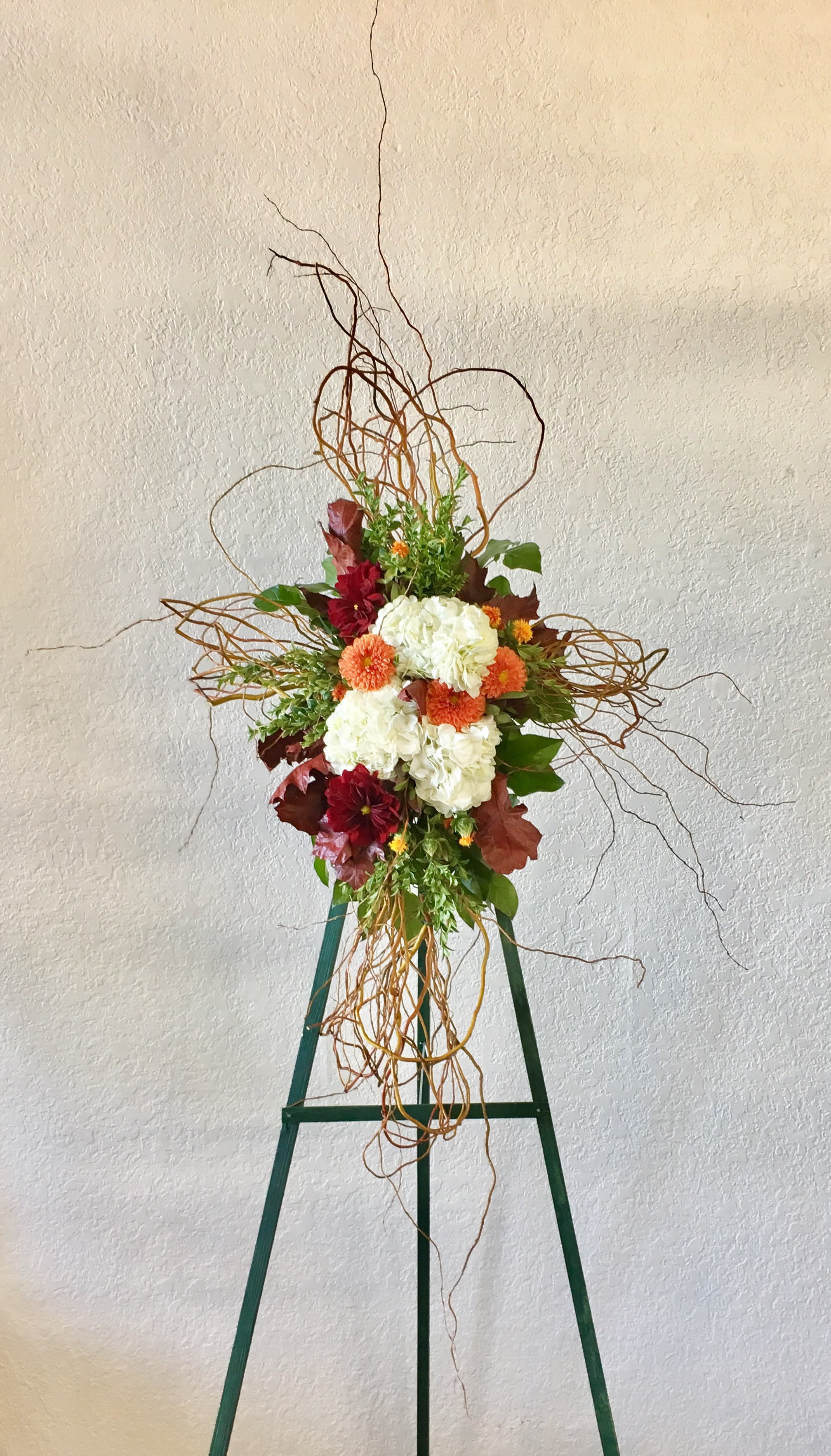 Tall floral arrangement with white and orange blooms on a green stand