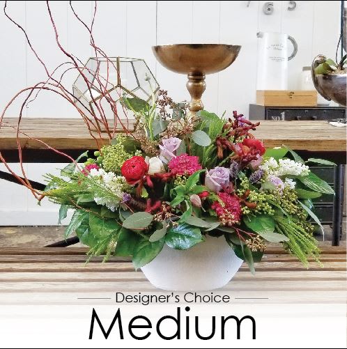Mixed floral arrangement in a white bowl vase with red, pink, and lavender blooms
