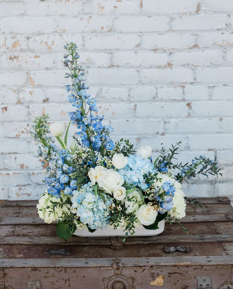 Blue and white floral arrangement in a low white container