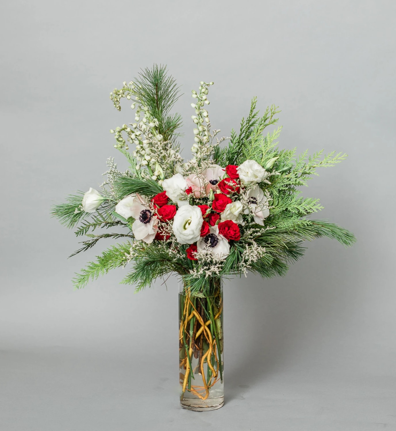 Mistletoe Memories - Get in the Holly Jolly Spirit with our dreamy Holiday Collection! Inspired by the warmth and memories of holidays past, Mistletoe Memories comes arranged with a variety of red and white premium blooms and textures, accented with holiday greens, all eloquently arranged in one of our hand-picked clear designer vases.  Pictured [DELUXE]  *Some items in this arrangement must be special ordered, please allow 1-2 weeks notice to allow time for arrival of special items, otherwise, substitutions will occur.*