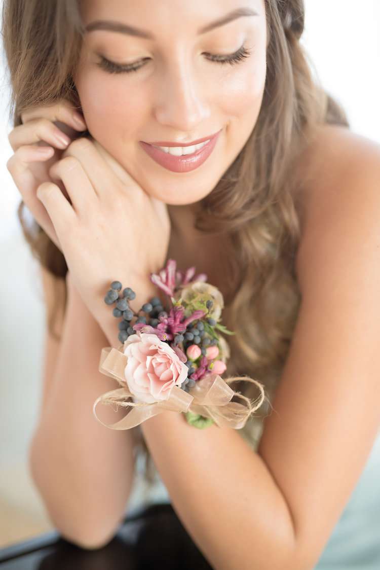 Woman wearing a floral wrist corsage with pink blooms and ribbon