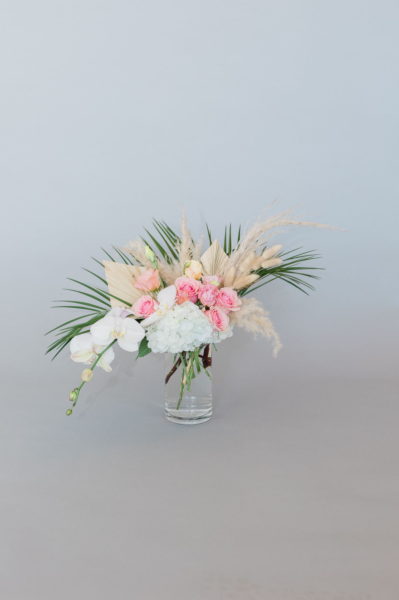 Pink roses and white orchids in a clear glass vase