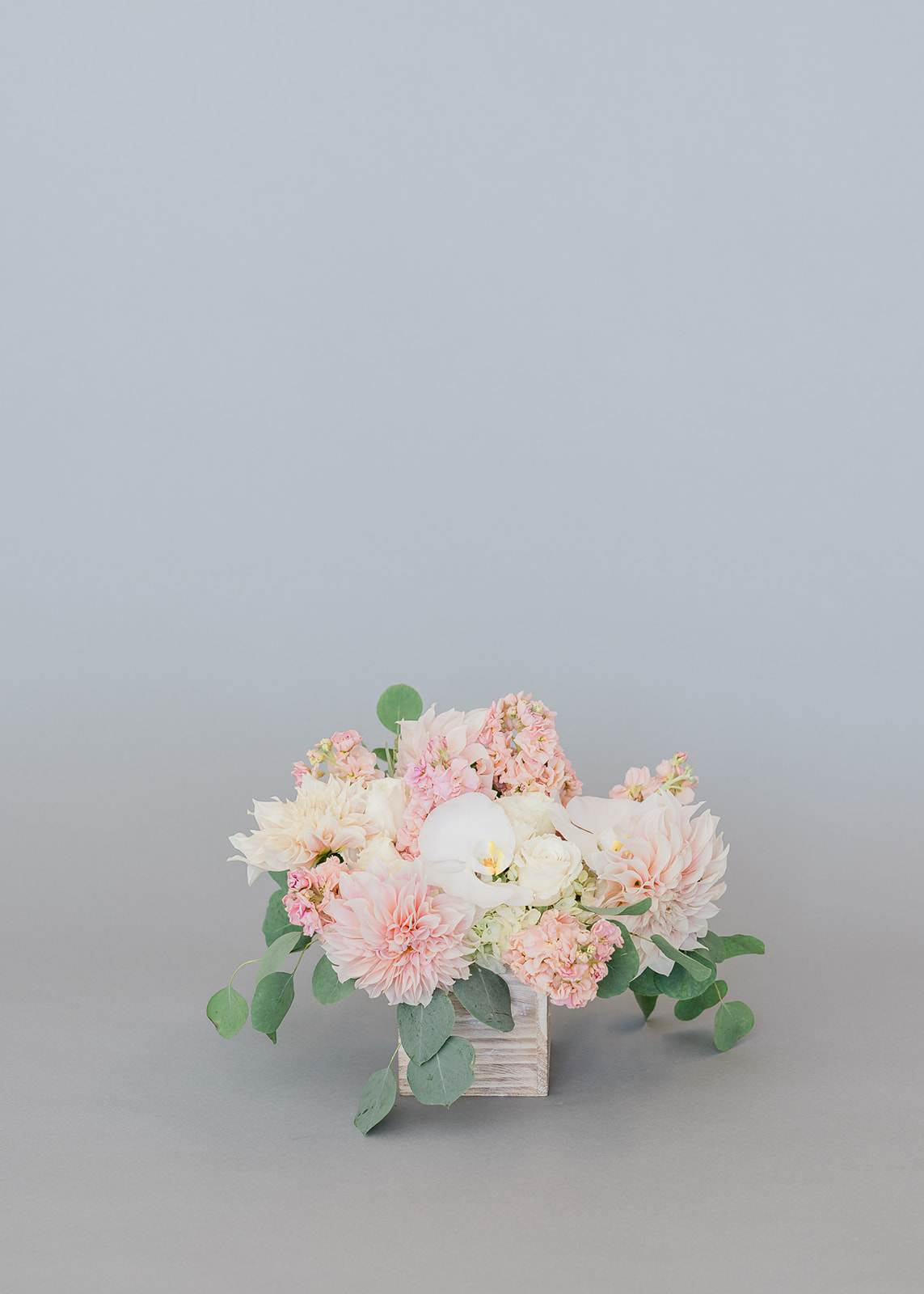 Blush and white floral arrangement in a wooden cube vase