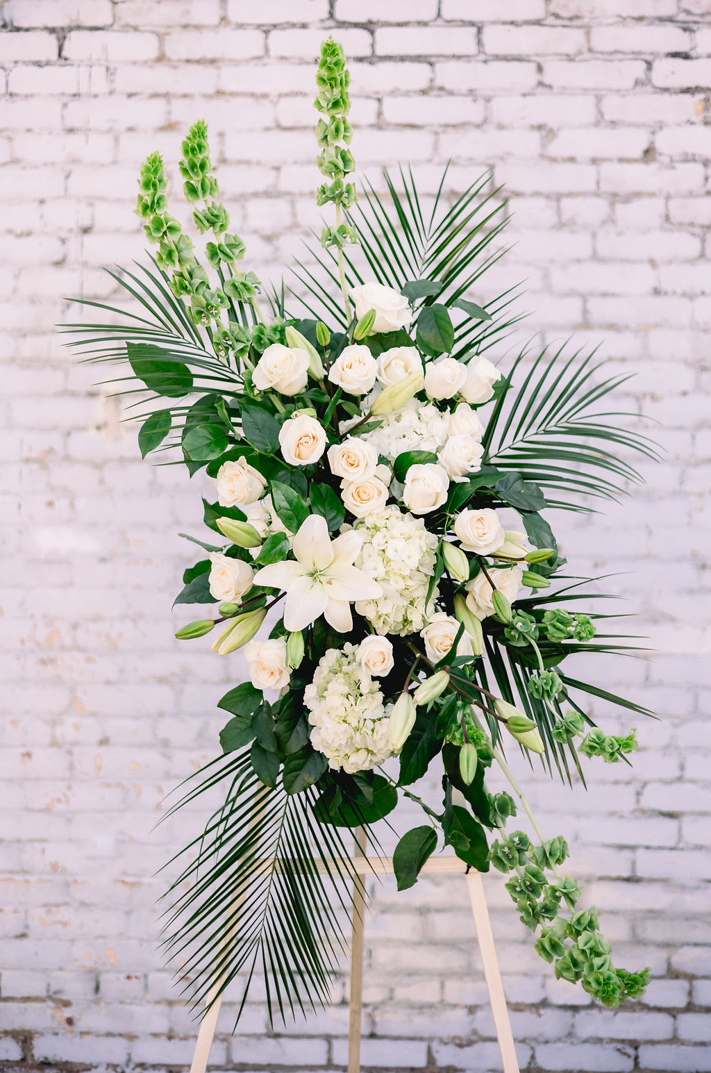 White floral standing spray with roses, lilies, and greenery