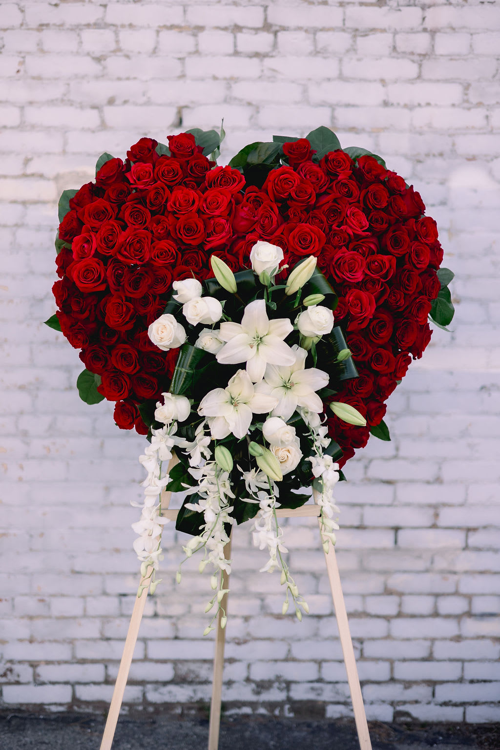 Heart-shaped red rose standing spray with white lilies and orchids