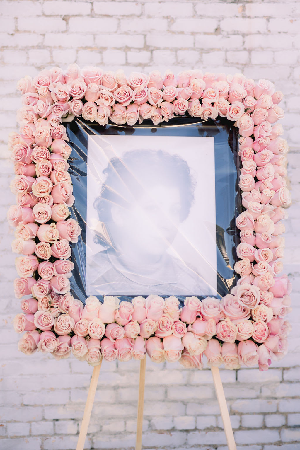 Square floral frame of pale pink roses around a portrait on an easel