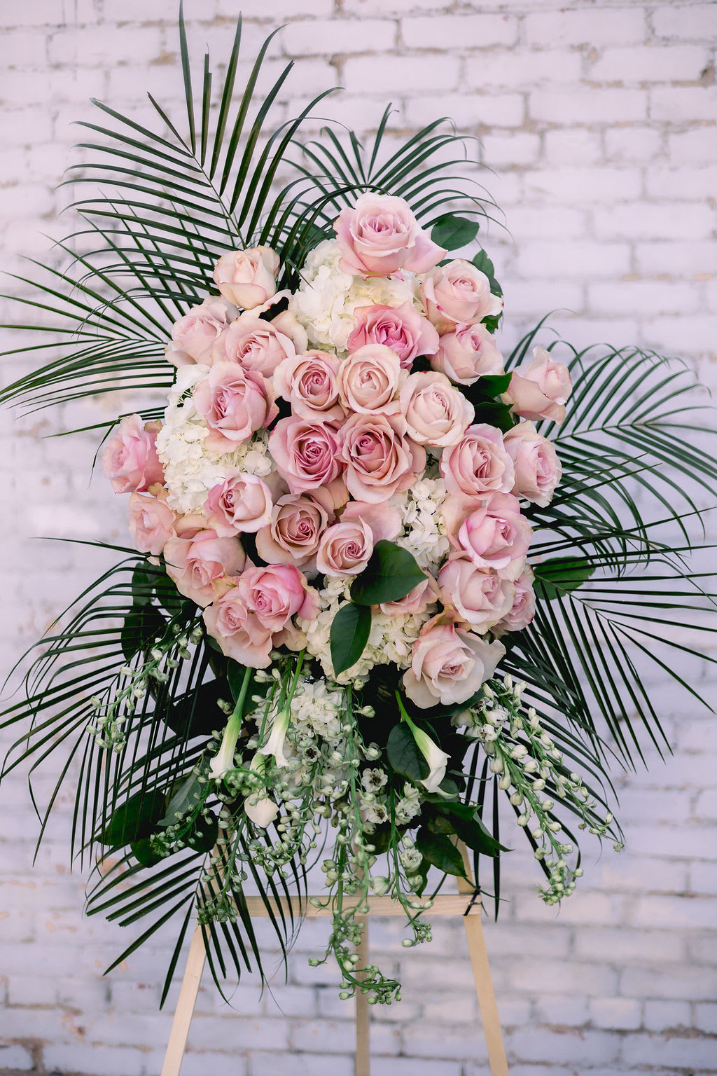 Pink rose standing spray with white flowers and palm fronds