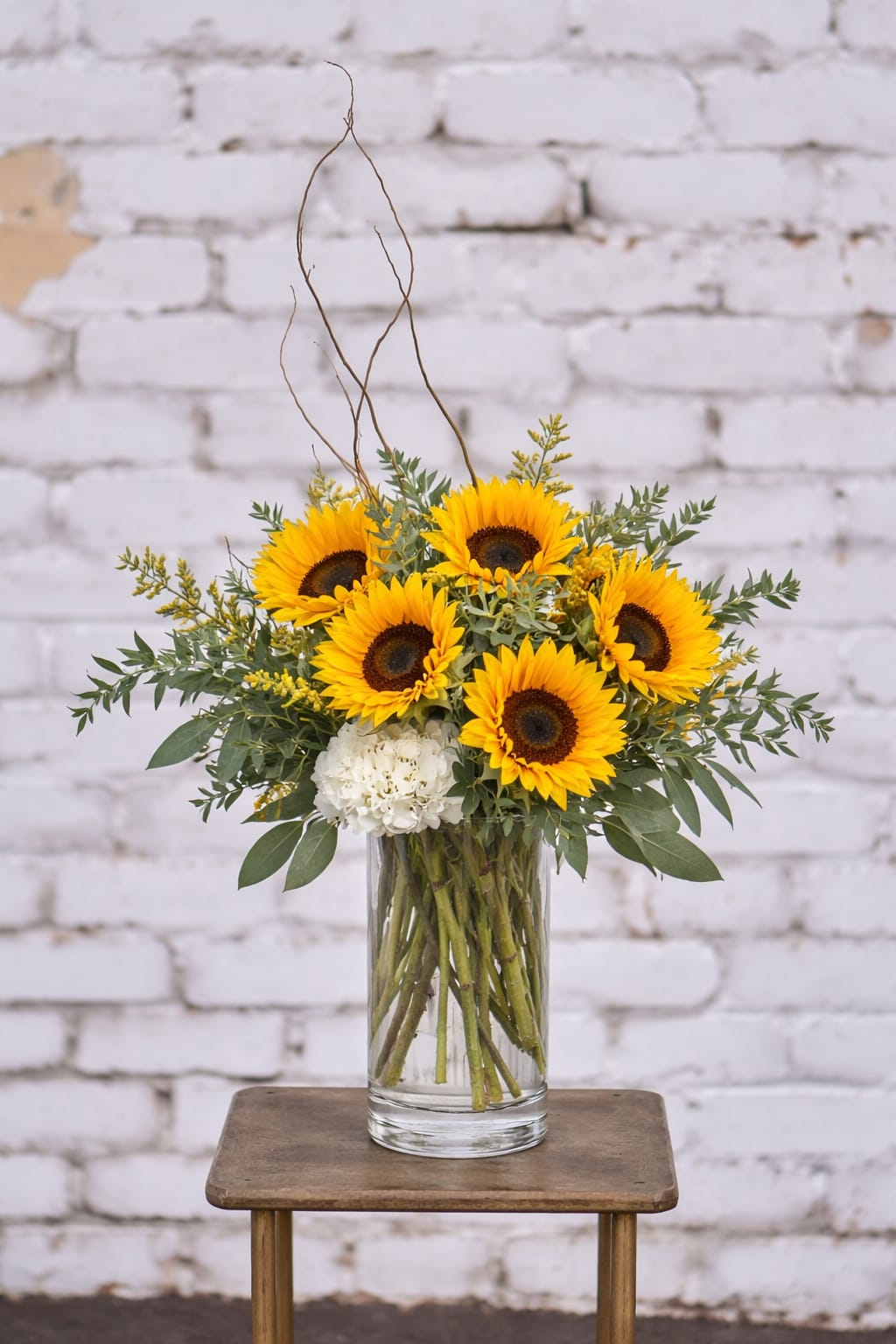 Sunflower arrangement in a clear glass vase with white accent blooms