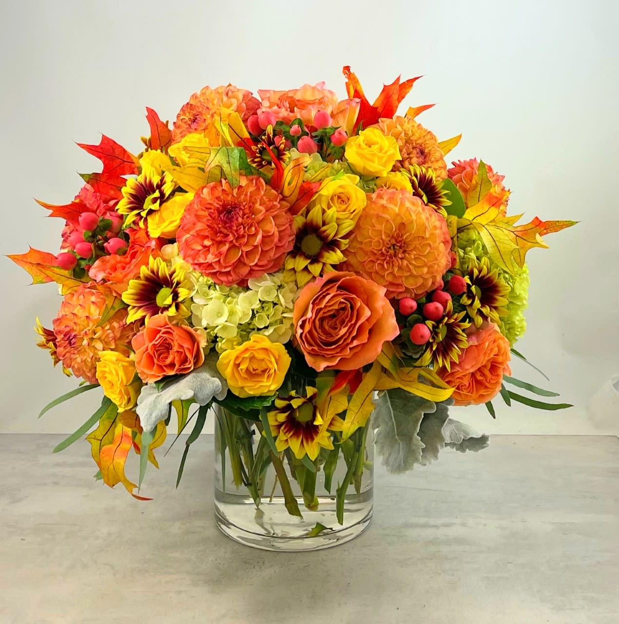Harvest Time Bouquet - Amber leaves, yellow and bronze mums, dahlias glowing peach and orange roses accented with orange hypericum eucalyptus and dusty Miller make the "Harvest Time" bouquet the perfect choice when looking share the spirit of Autumn with friends and loved ones.