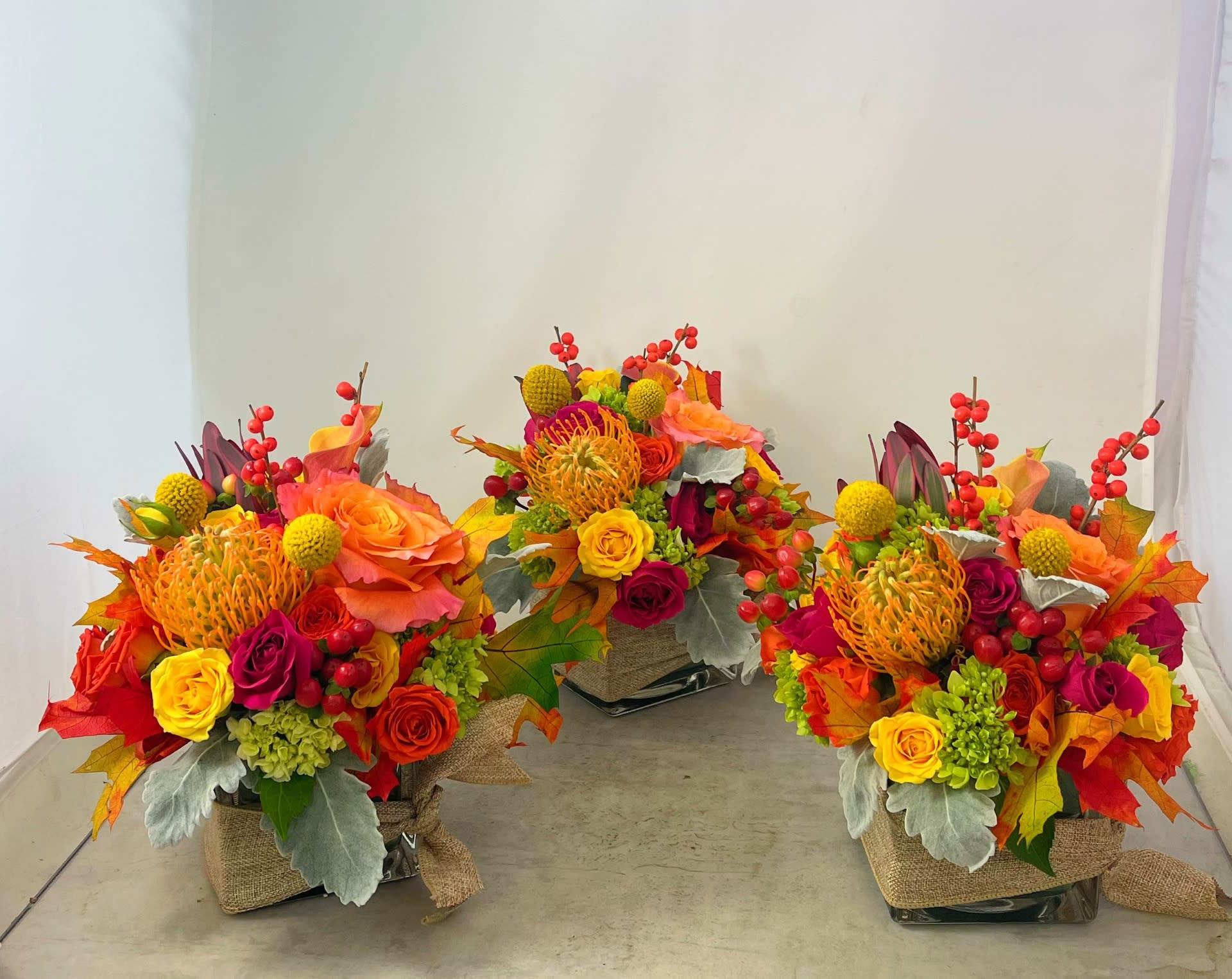 Thanksgiving Trio - Why have one centerpiece when you can have three!!!  Space three smaller designs tied with burlap ribbon artfully down the center of the table, leaving ample room for the main attraction. Having three centerpieces also gives you the opportunity to share the floral "bounty" with your guests!