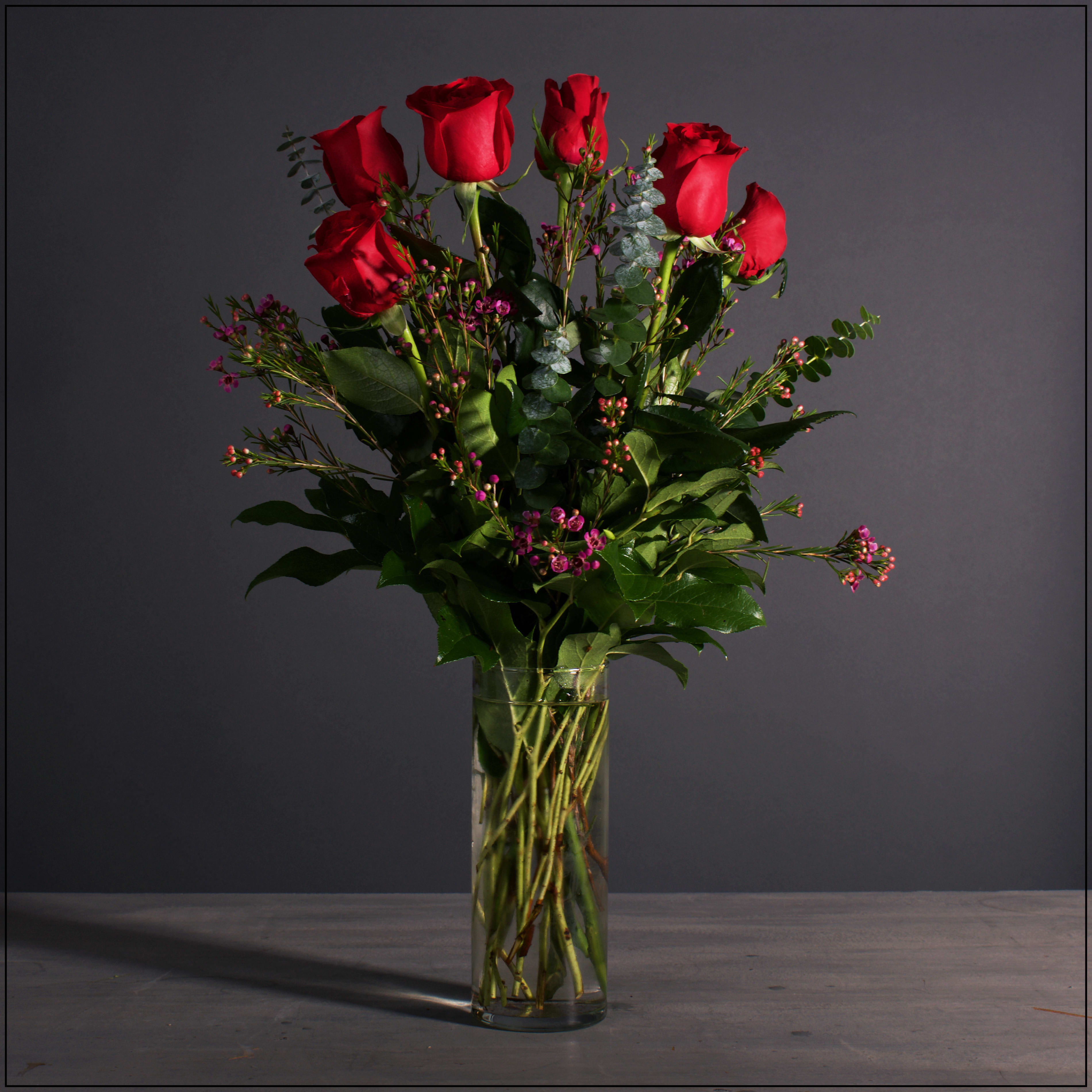 Red roses in a clear glass vase with small pink filler flowers
