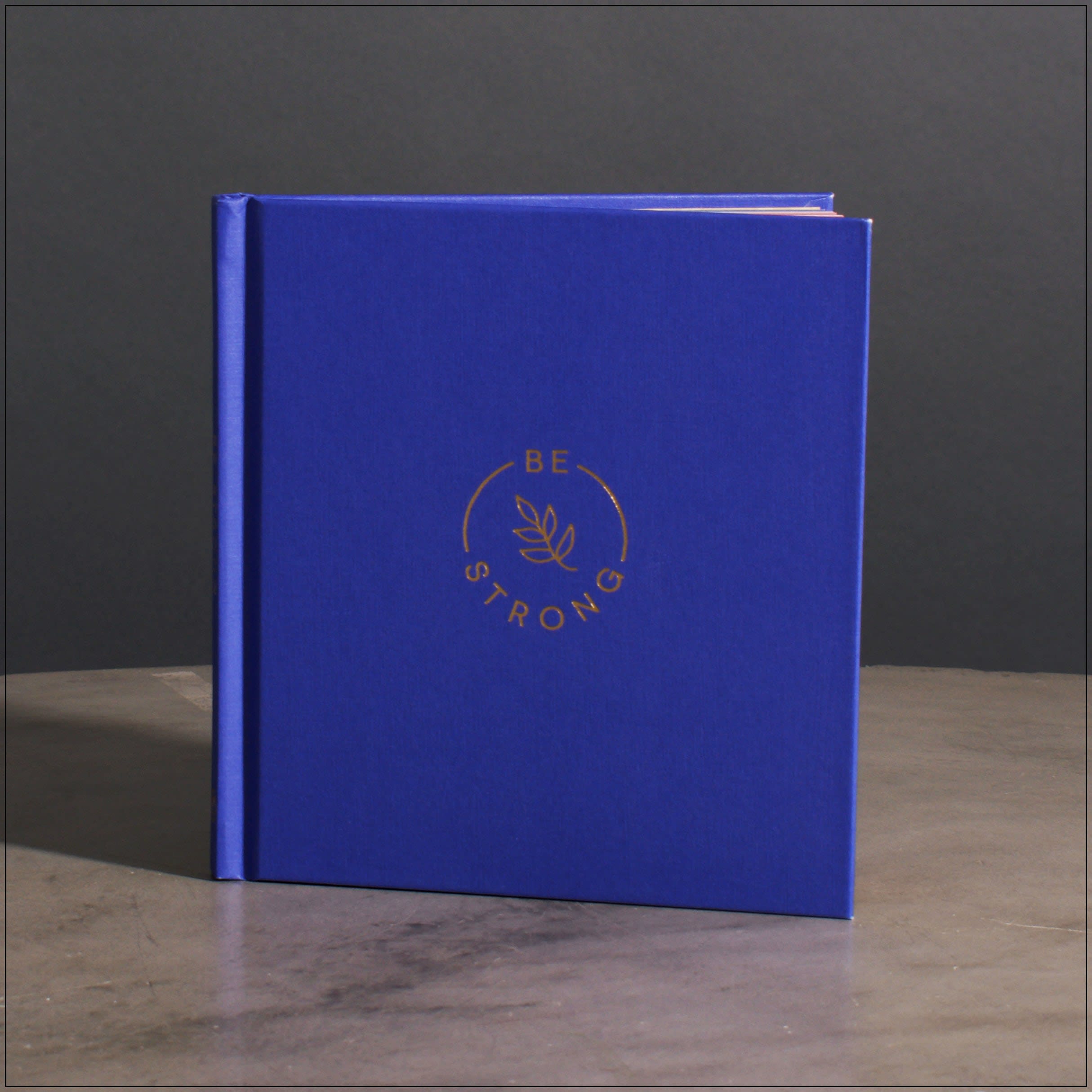 Blue hardcover book with gold "Be Strong" logo on the cover