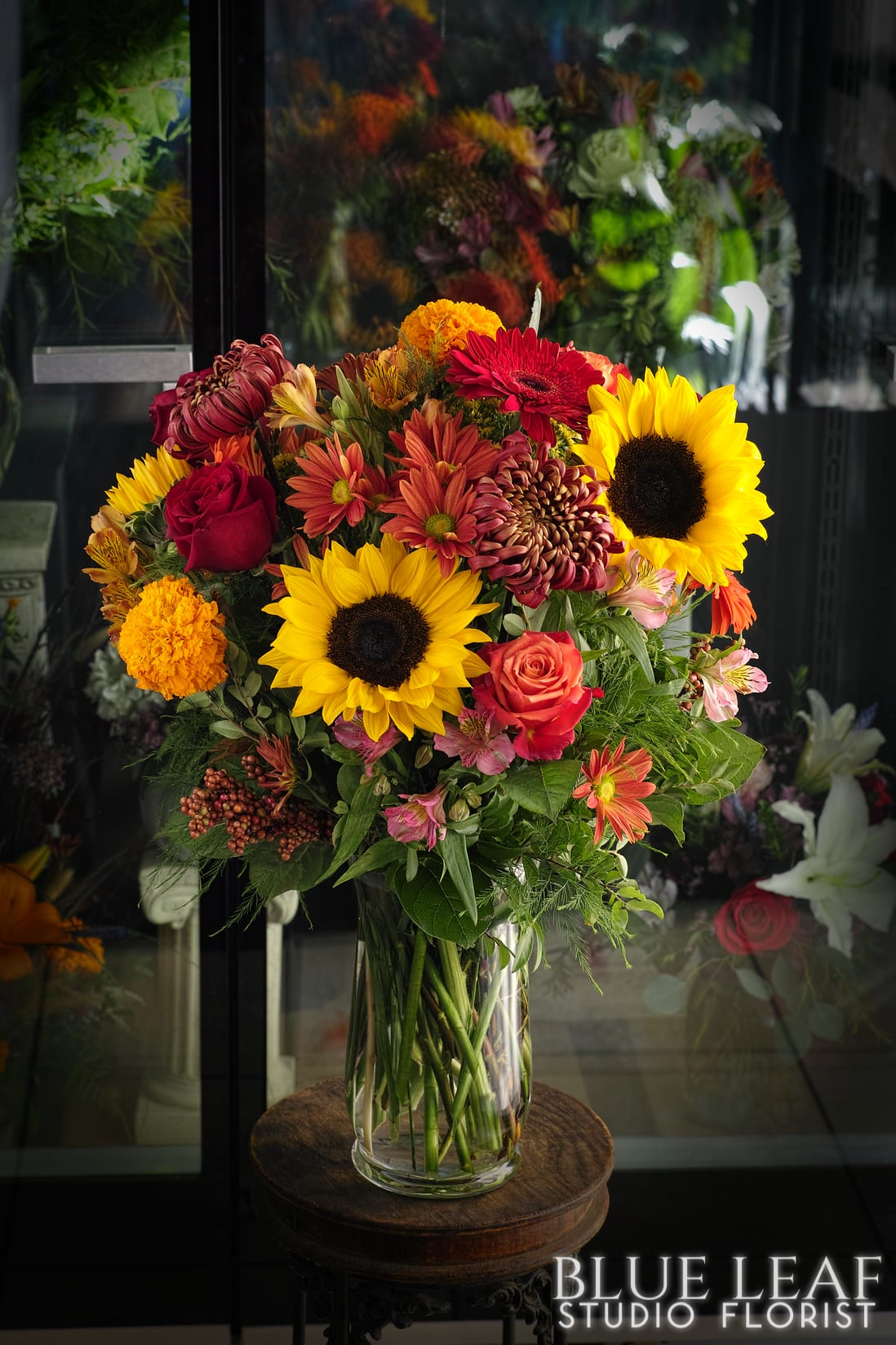 Mixed bouquet of sunflowers, roses, and chrysanthemums in a glass vase