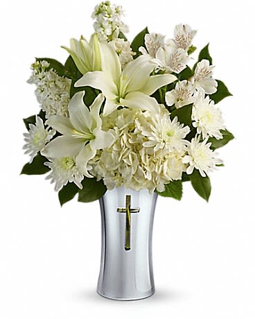 White lilies and daisies arranged in a silver vase with a cross