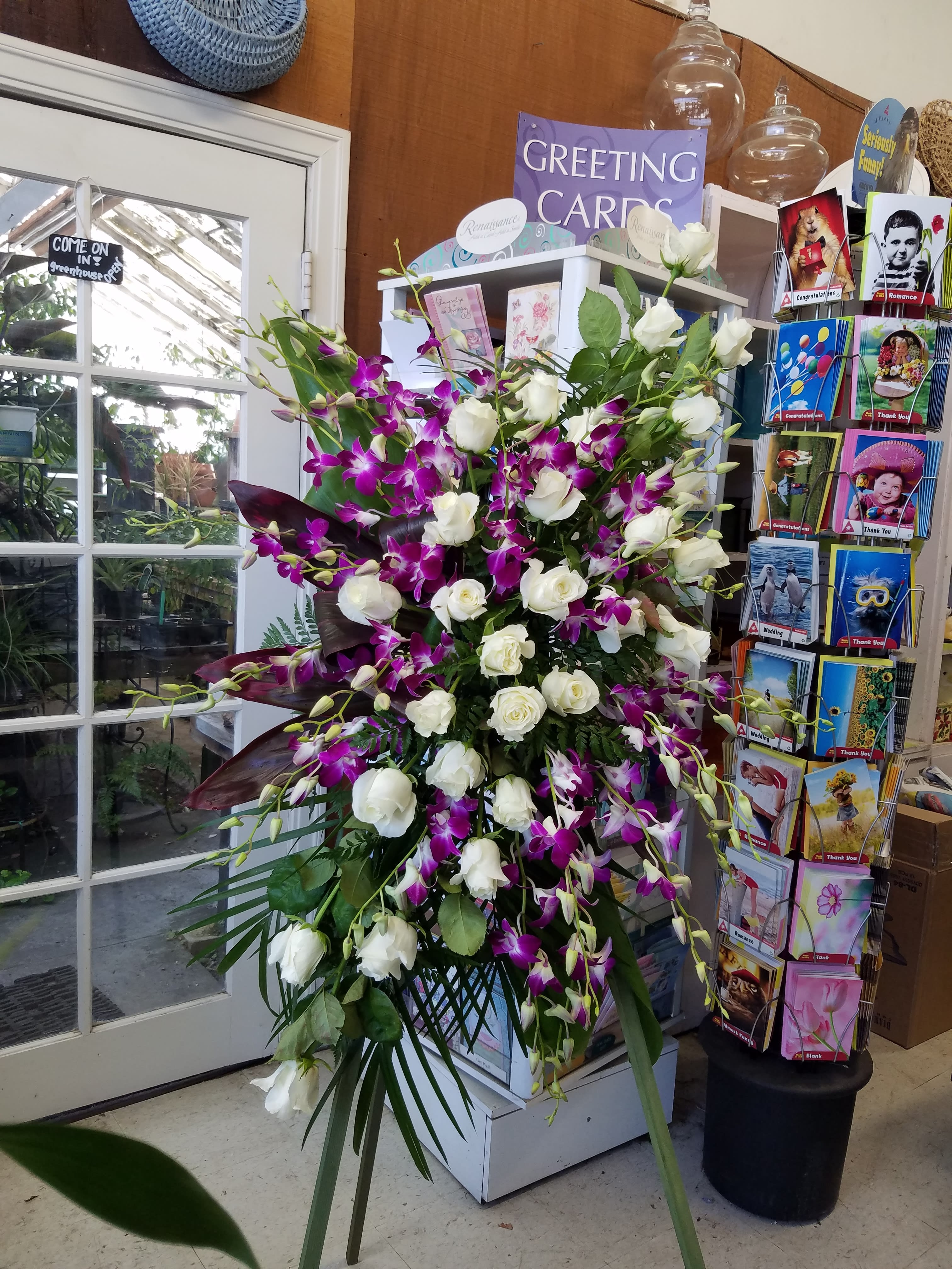 Tall arrangement of white roses and purple orchids on a stand