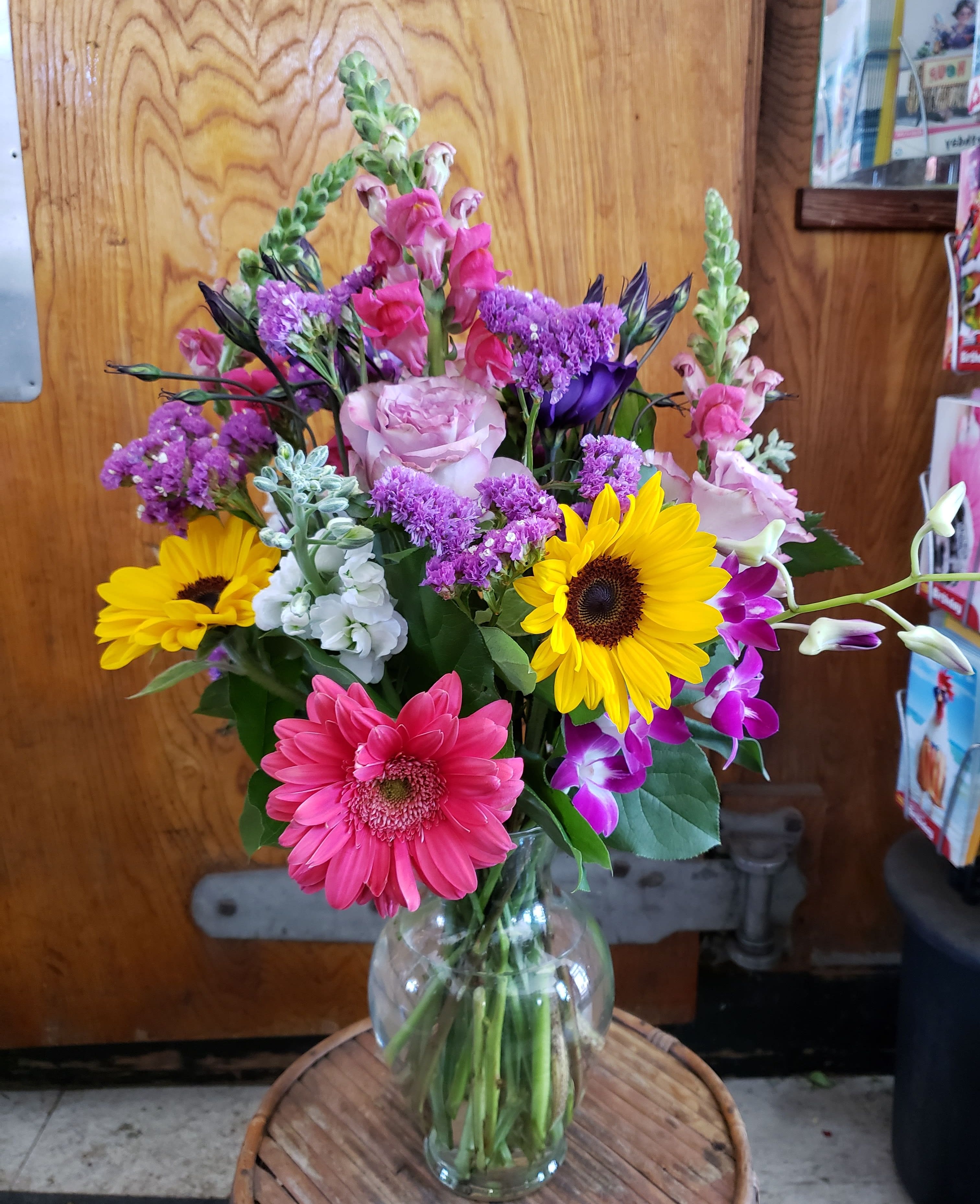 Mixed bouquet in a clear glass vase with pink, yellow, purple, and white flowers