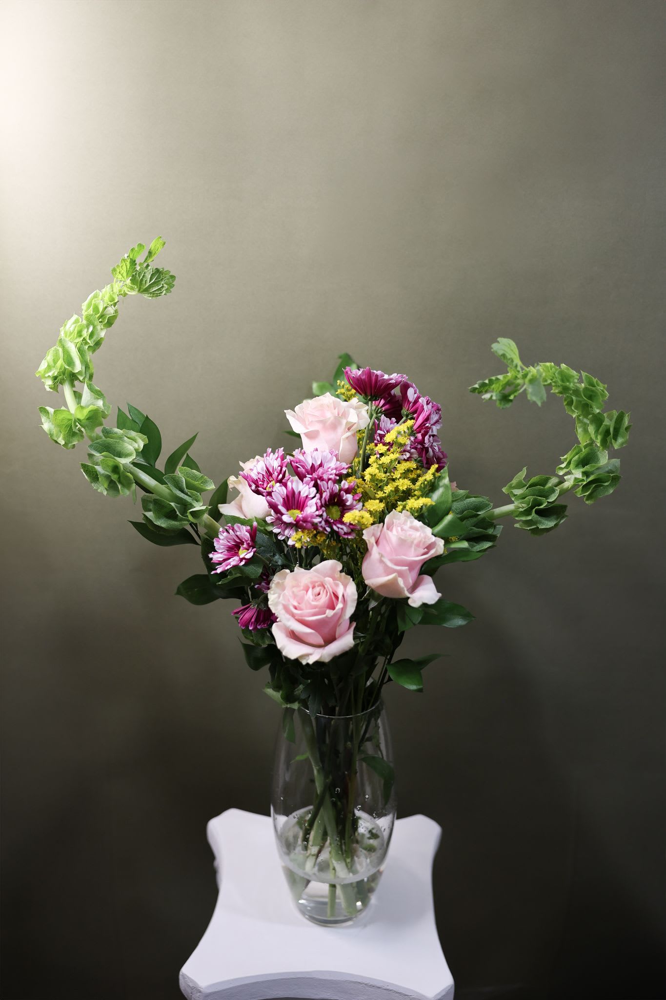 Pink roses and purple daisies in a clear glass vase