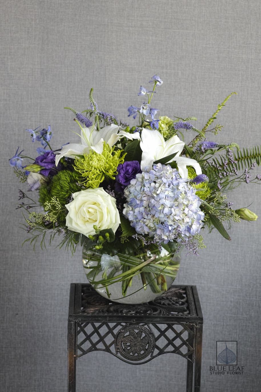 White lilies, roses, and lavender hydrangea in a glass vase