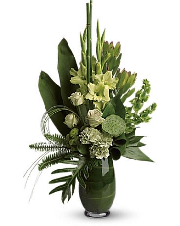 Tall green and white arrangement with roses, carnations, and tropical greenery in a green glass vase