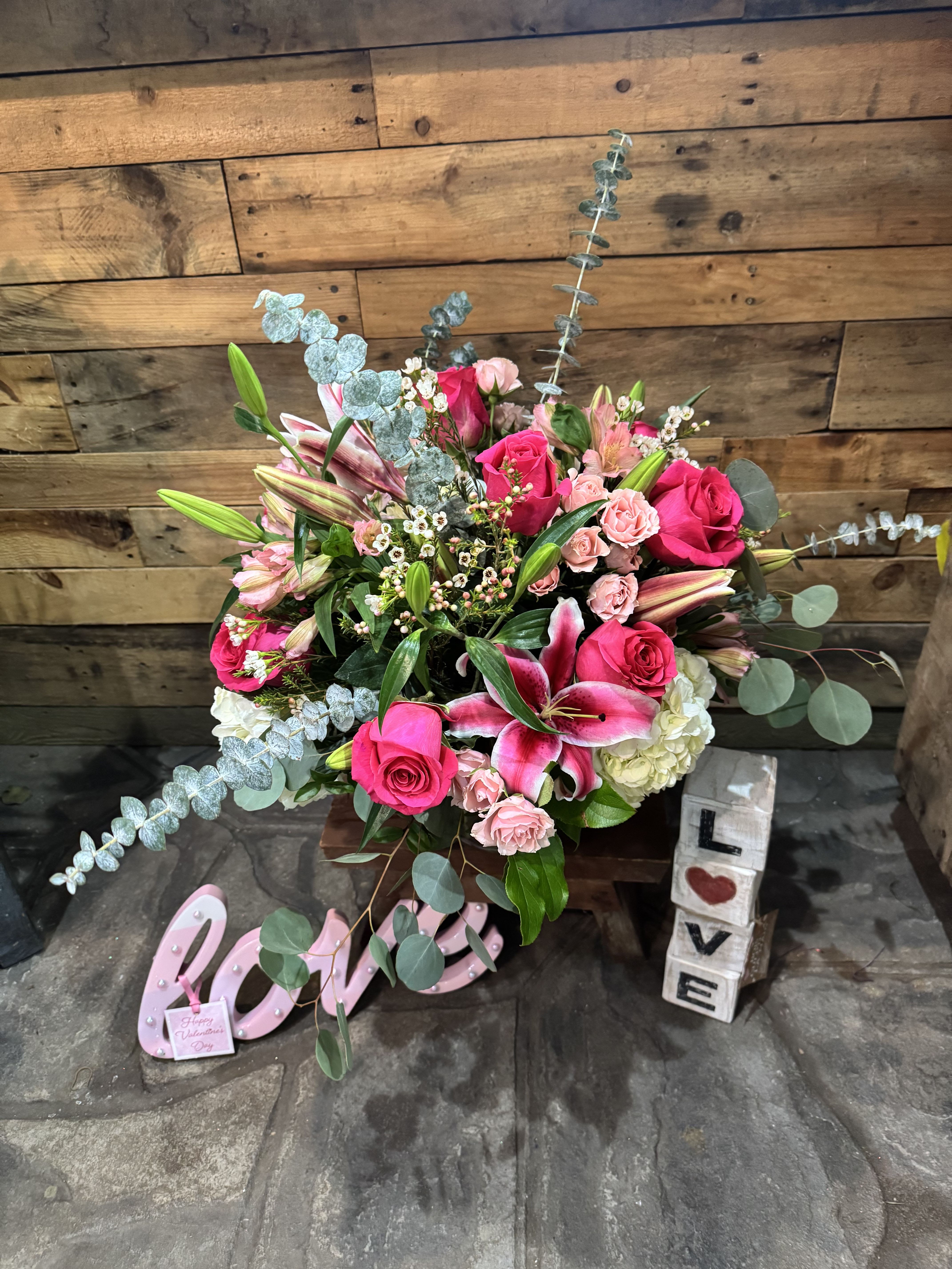Pink roses and lilies arranged with eucalyptus in a decorative display