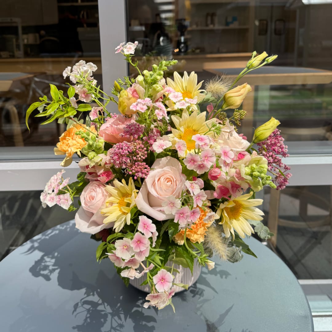 Mixed pastel bouquet in a white vase with roses and daisies