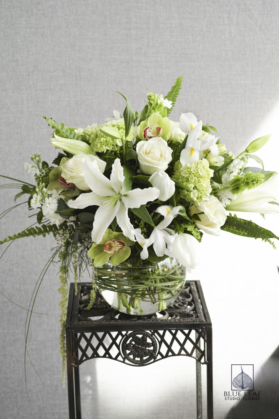 White and green floral arrangement in a glass bowl vase