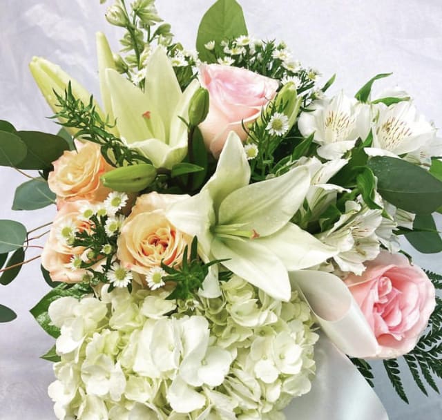 Bouquet of white lilies, pink and peach roses, and white hydrangea