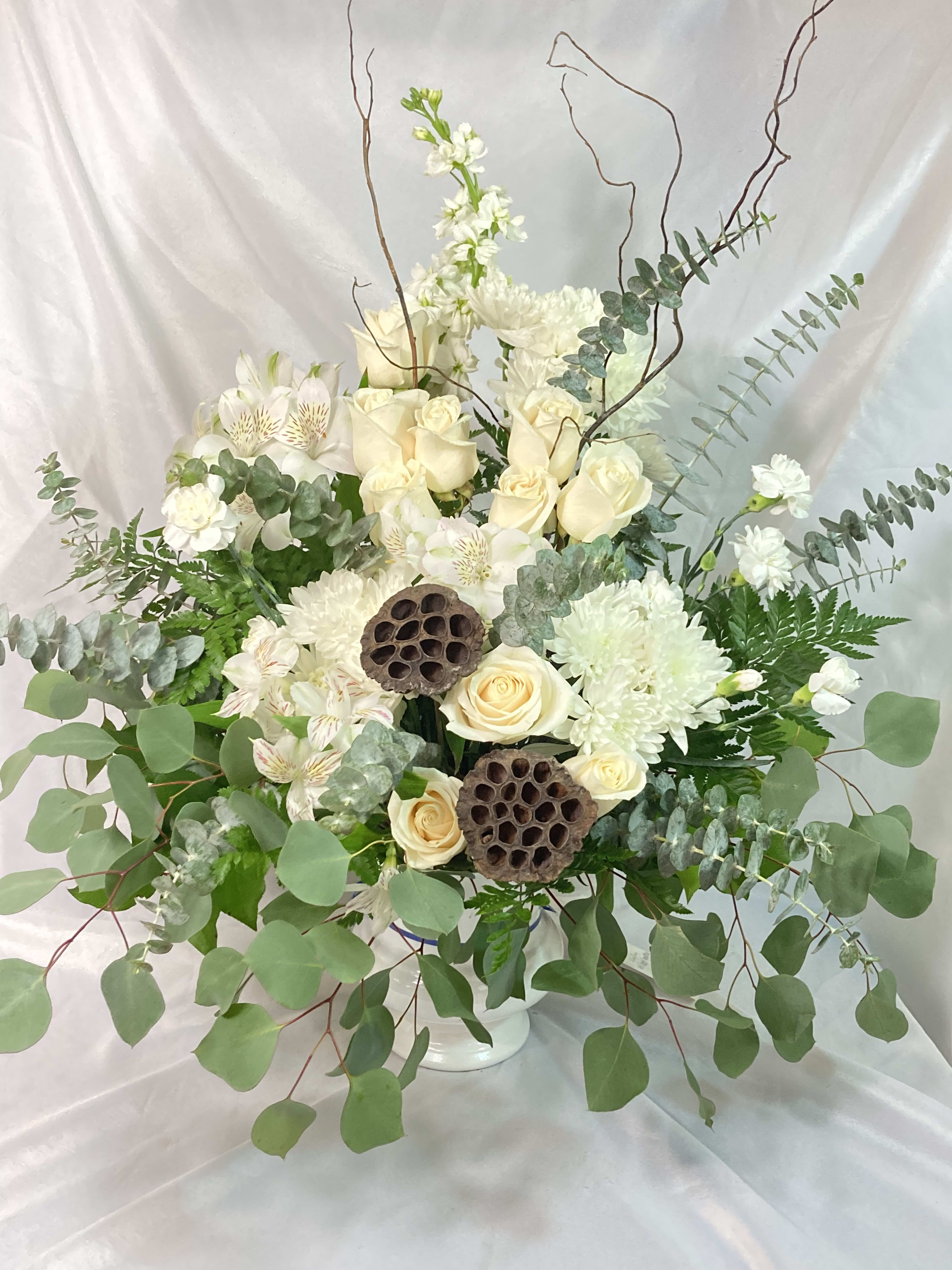 White roses and chrysanthemums in a white vase with eucalyptus and lotus pods