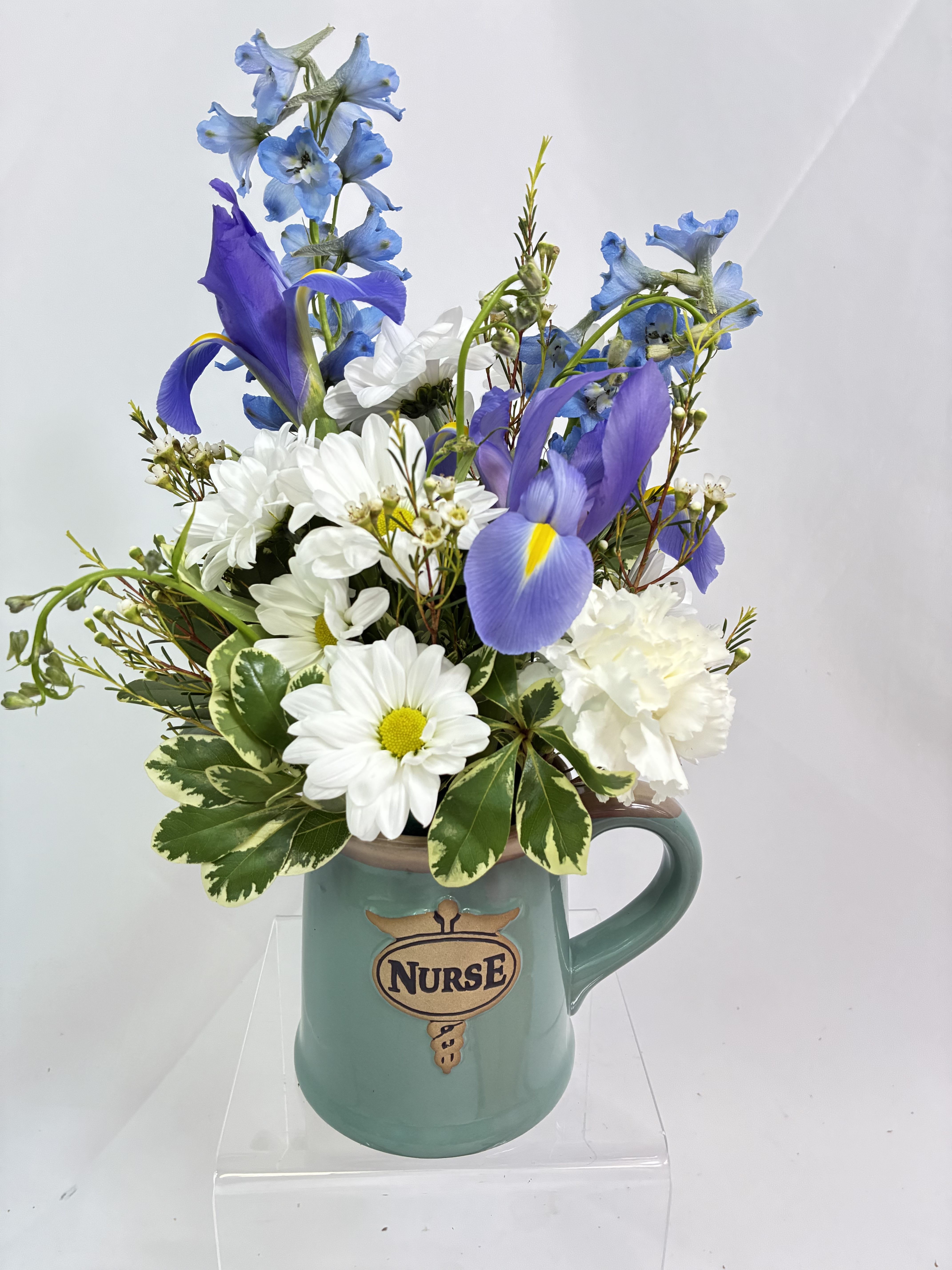 Nurses Cup of Blooms - Thank you to all the nurses that work  so hard and all you do! This Nurse‘s Mug is a keepsake to be used again and again. This gift of fresh blooms, includes Chrysanthemums, Iris‘s and Delphinium‘s is the perfect way to say thank you to that special Nurse!