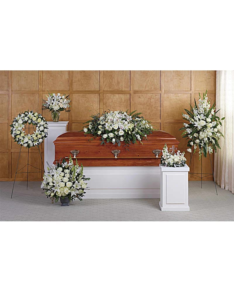 Funeral casket surrounded by white floral arrangements