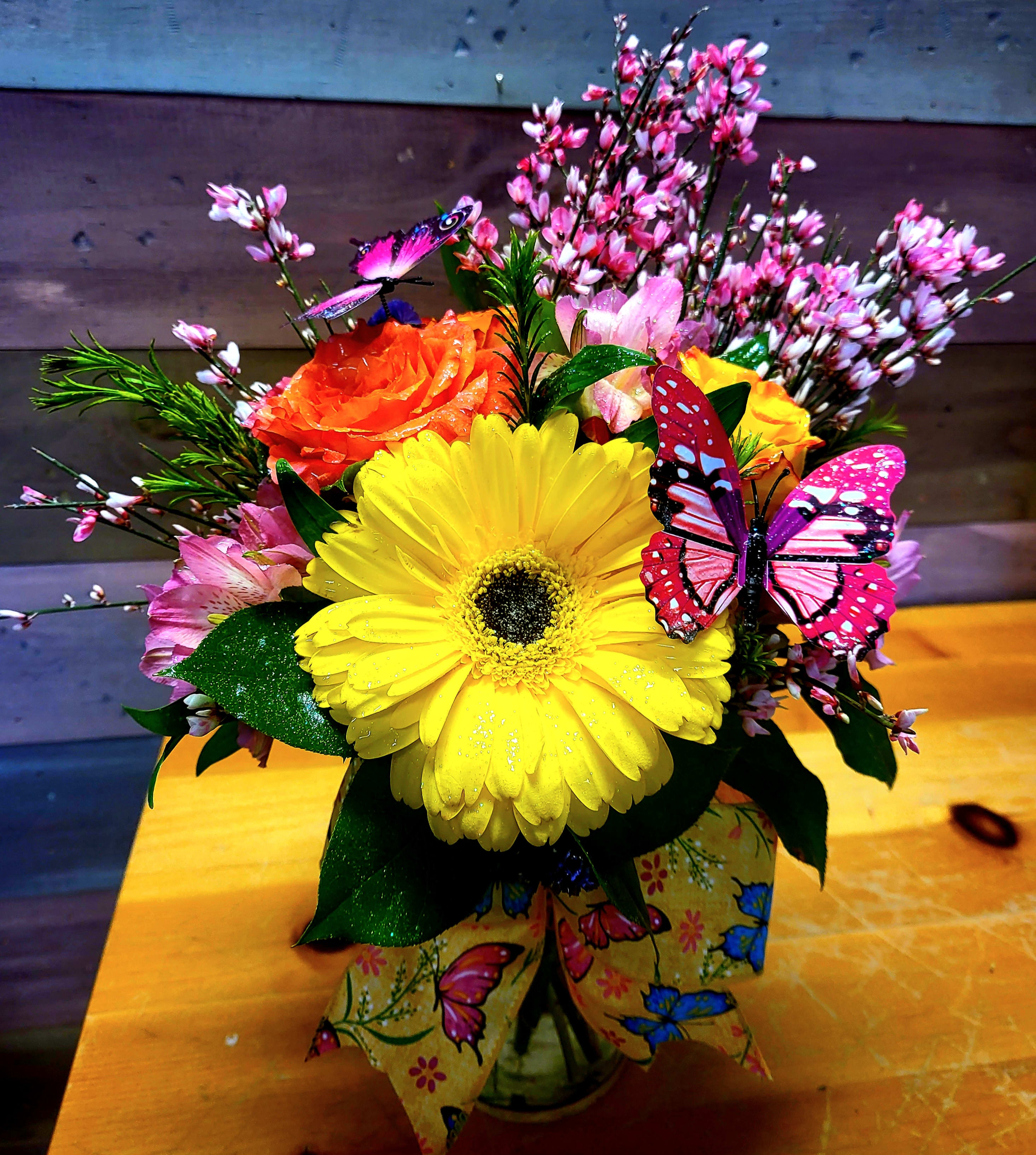 Bright mixed bouquet with a yellow gerbera and orange rose in a butterfly-decorated vase