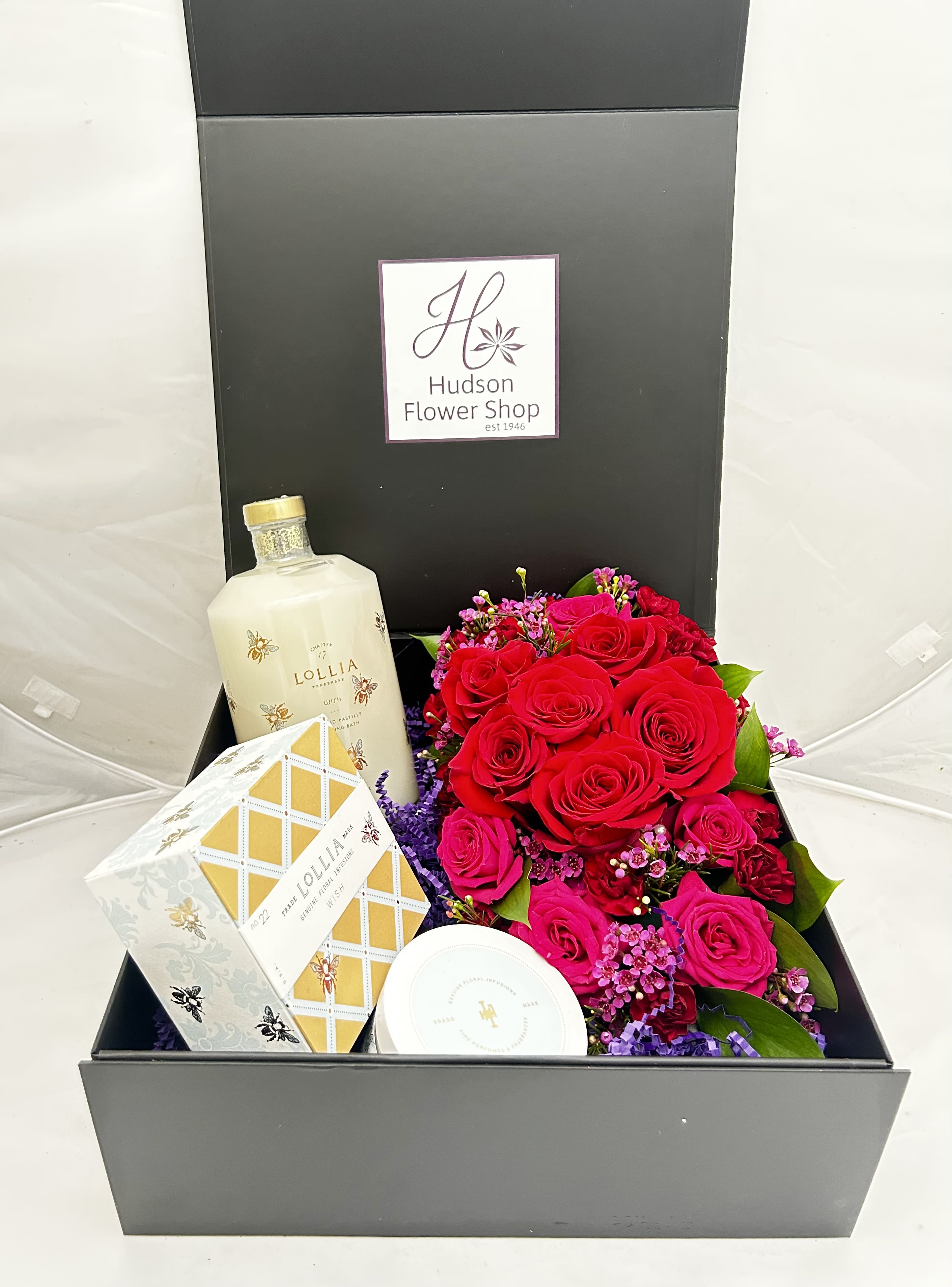 Boxed gift set with red roses, a bottle, and packaged bath items