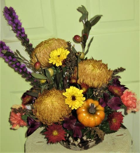 Autumn floral arrangement with yellow blooms and a small pumpkin