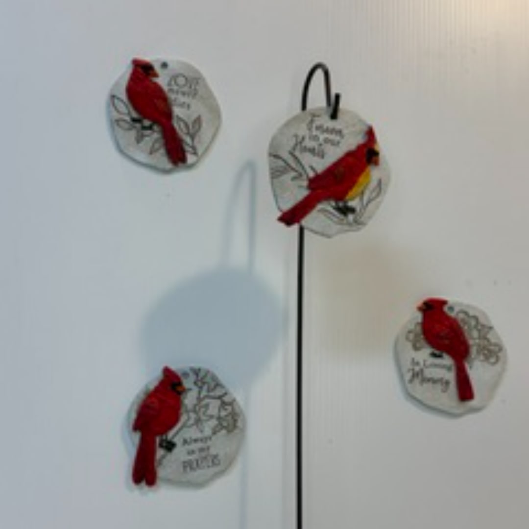 Four decorative cardinal ornaments on a wall, each with a red bird and text