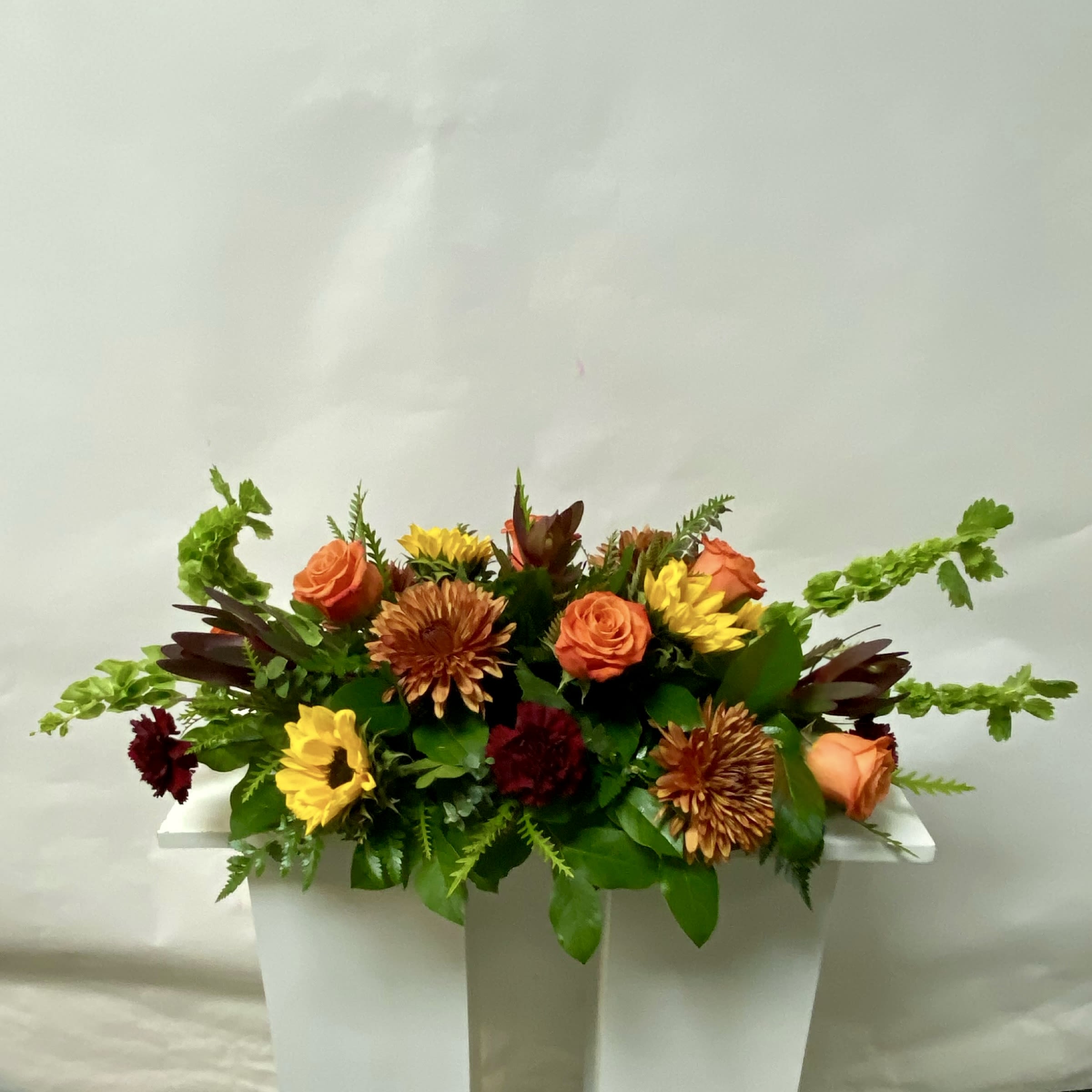 Orange and yellow mixed flower arrangement in a white container
