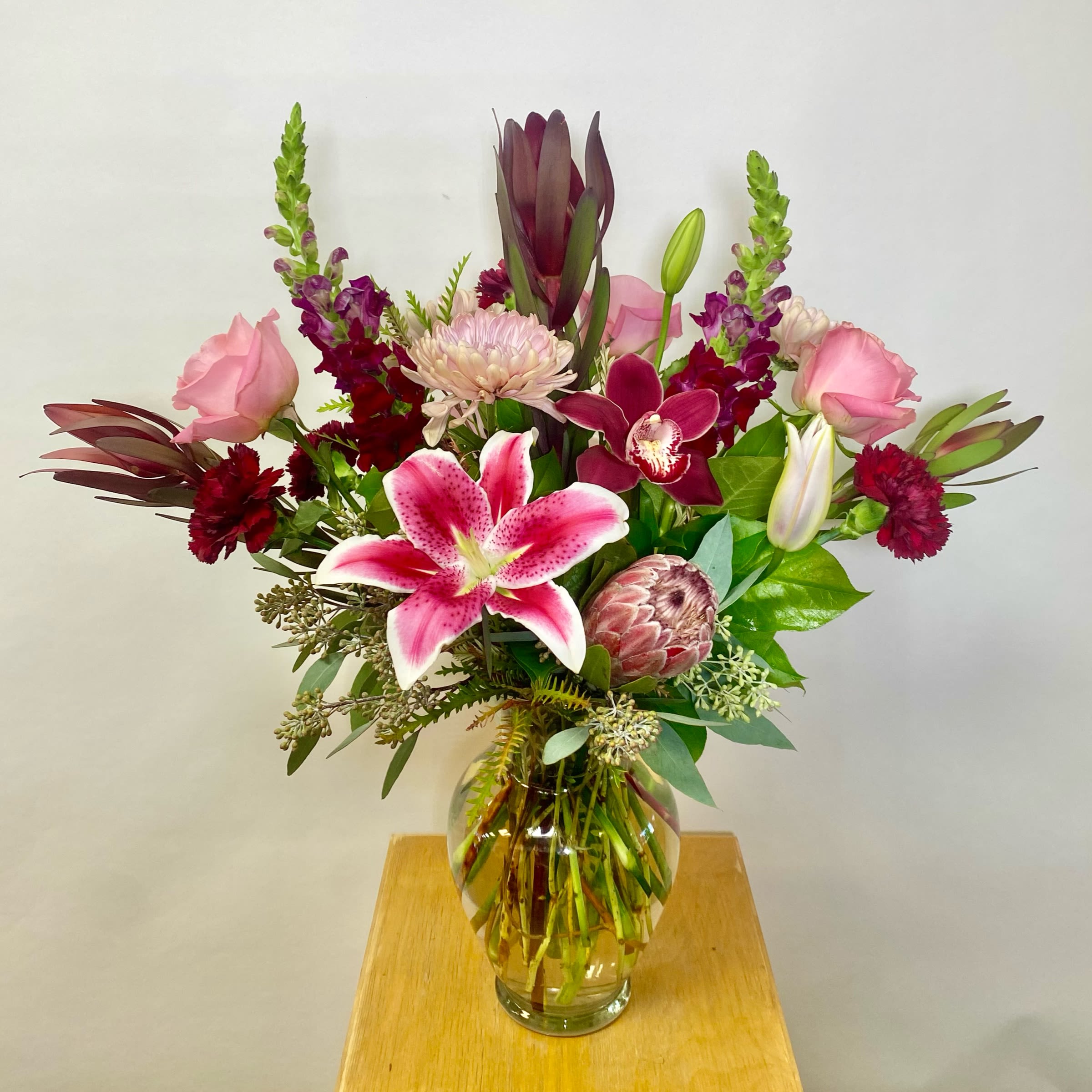 Mixed pink and burgundy flowers in a clear glass vase