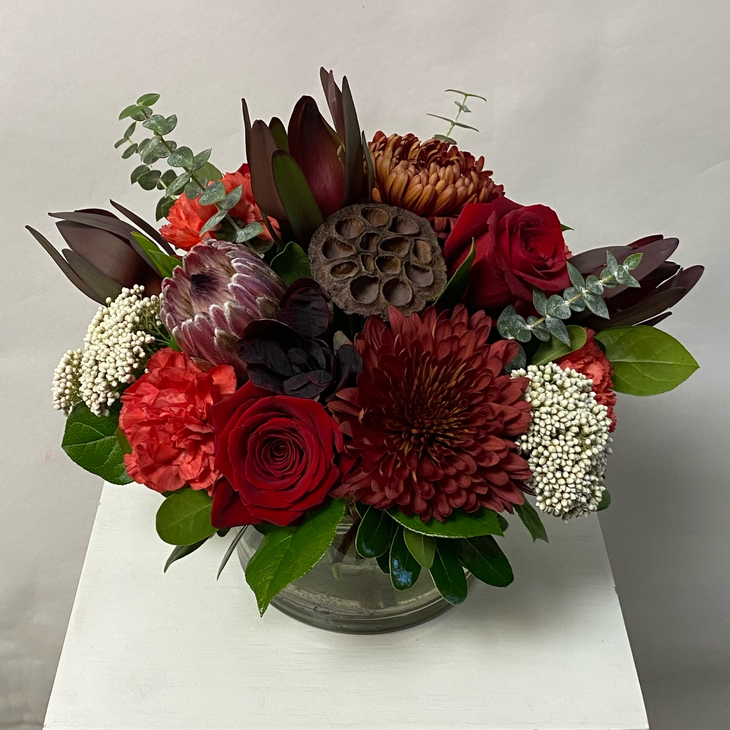 Red and burgundy floral arrangement in a clear glass vase